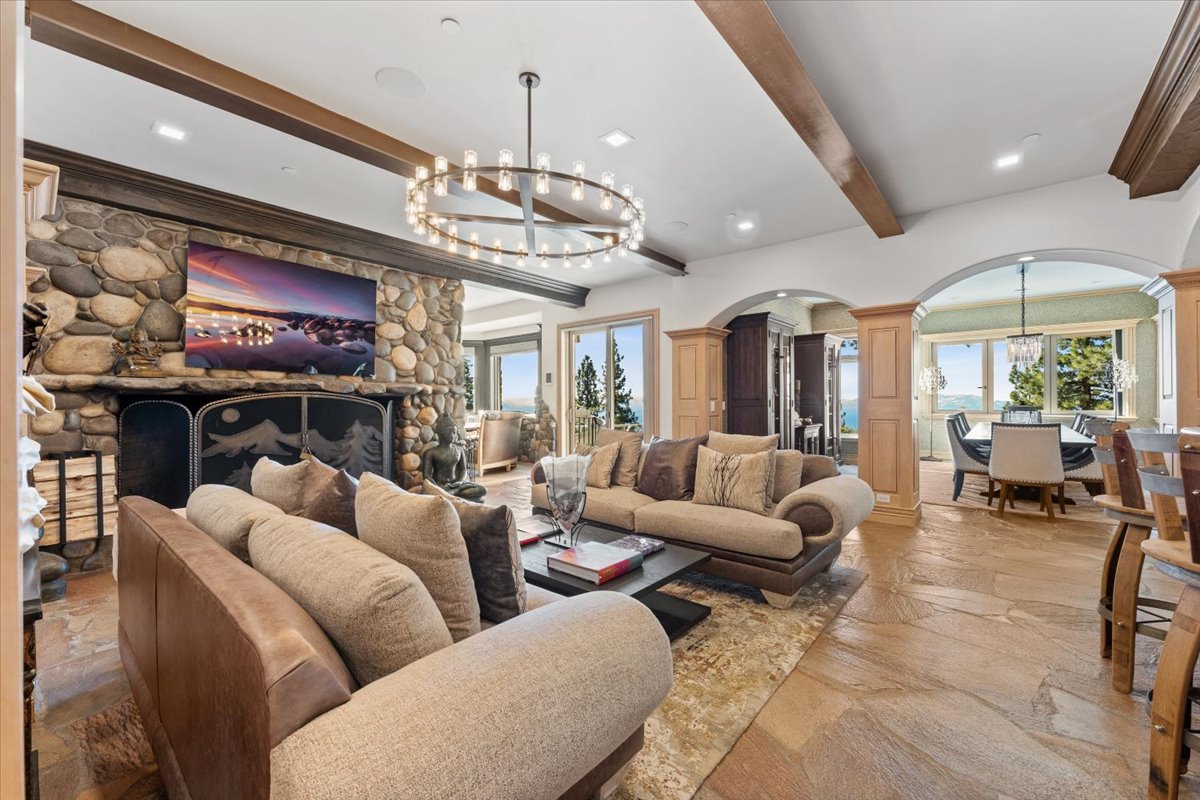 The family room offers a cozier atmosphere around a river rock fireplace, with exposed wood beams overhead.