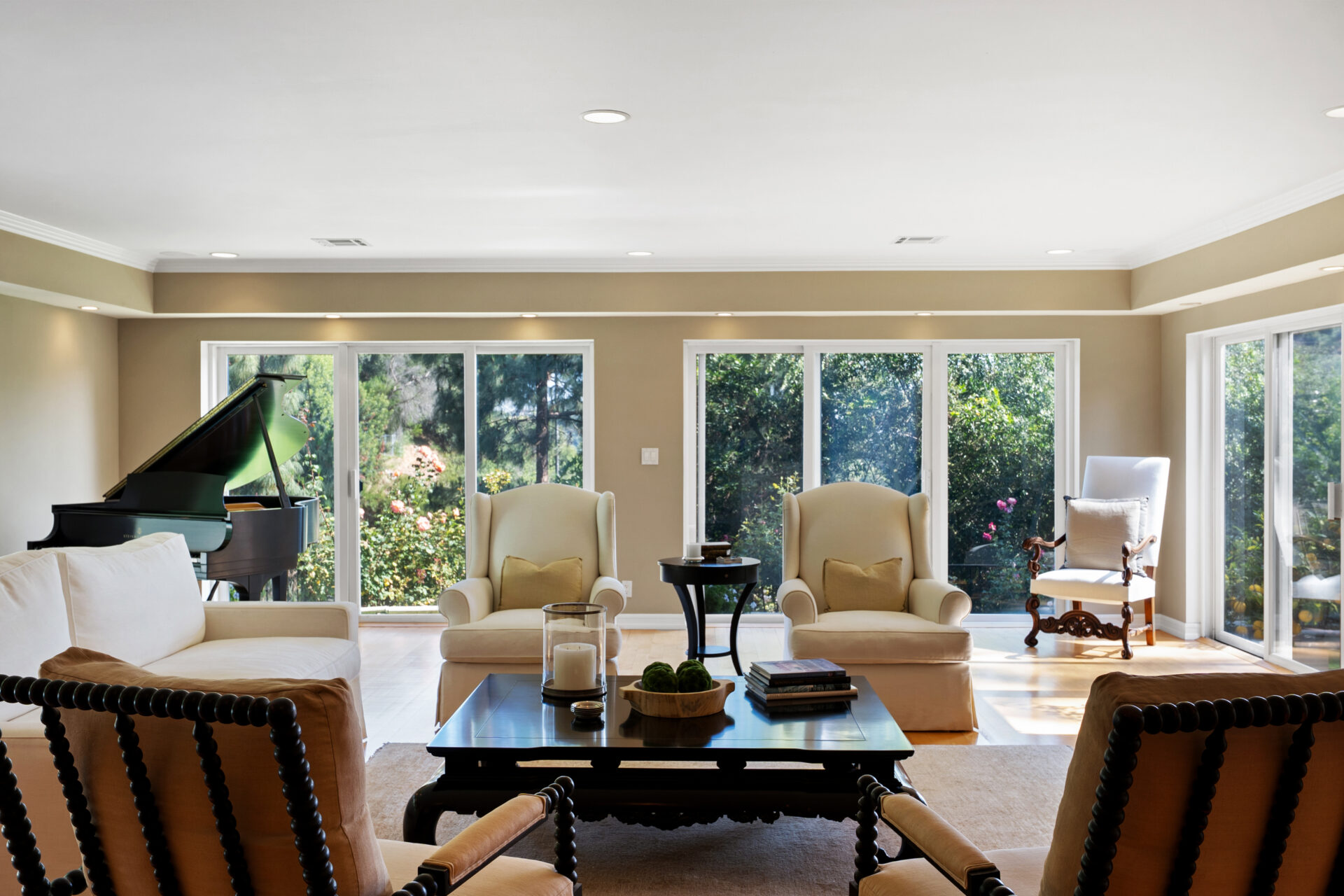 The room is arranged around a central sitting area with a grand piano positioned beside the windows.