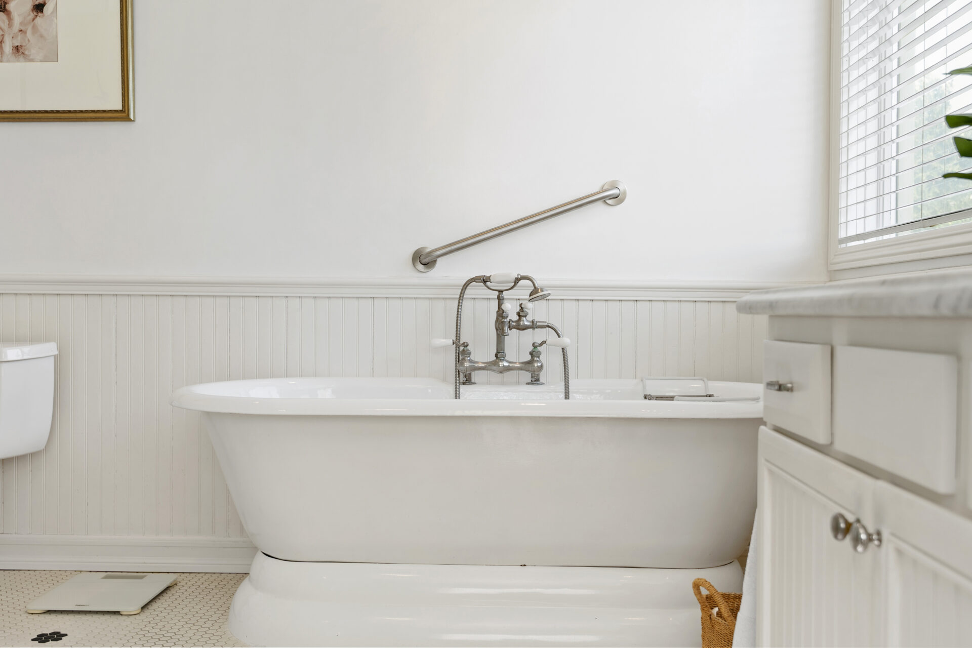 A white freestanding soaking tub between a toilet and vanity.