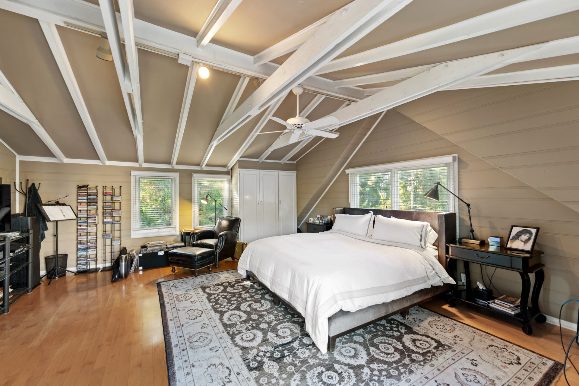 The secondary suite is placed beneath a vaulted ceiling with exposed white-painted beams.