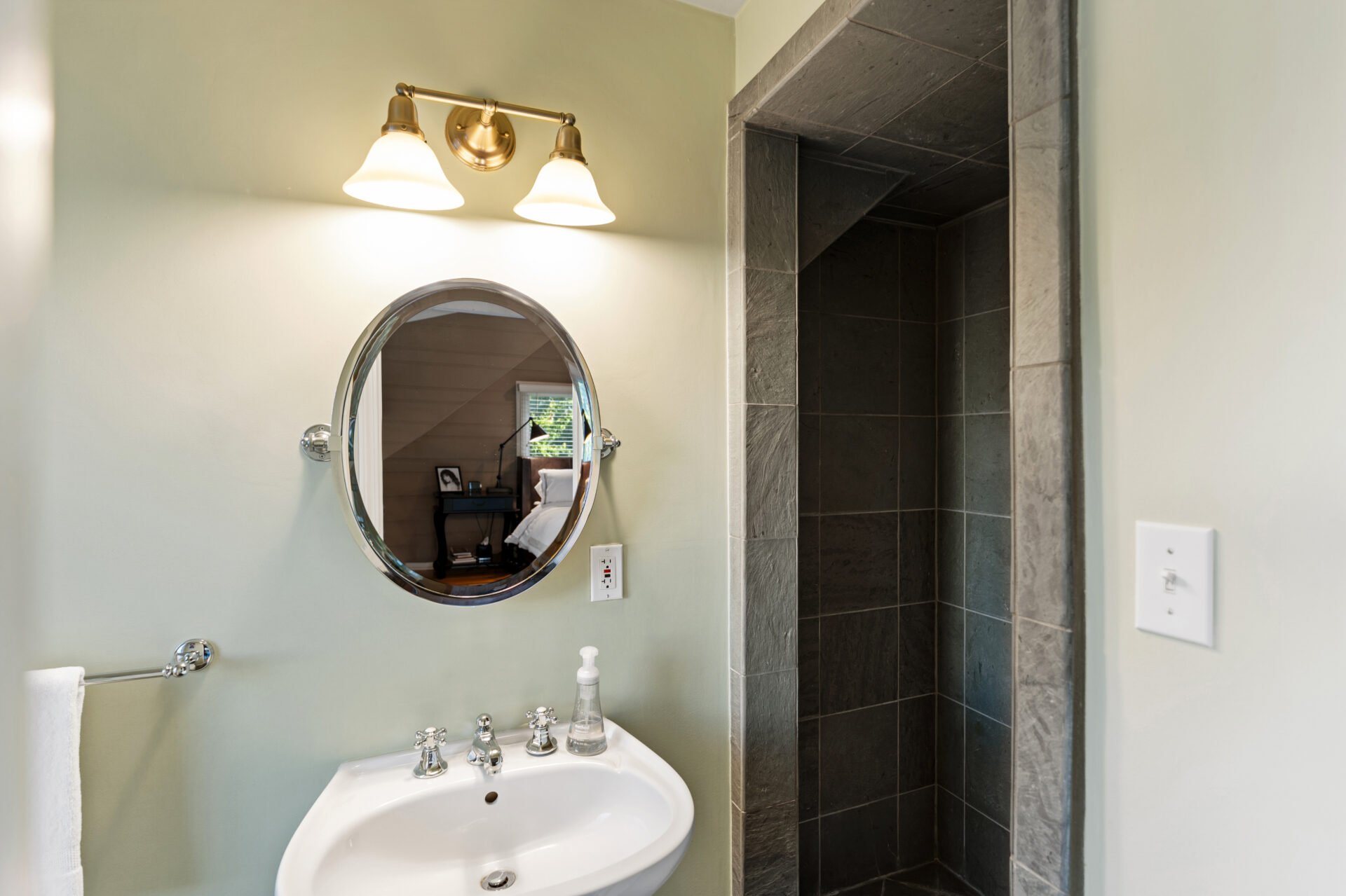 Small bathroom featuring a pedestal sink, an oval mirror, and a walk-in shower in dark slate tile.