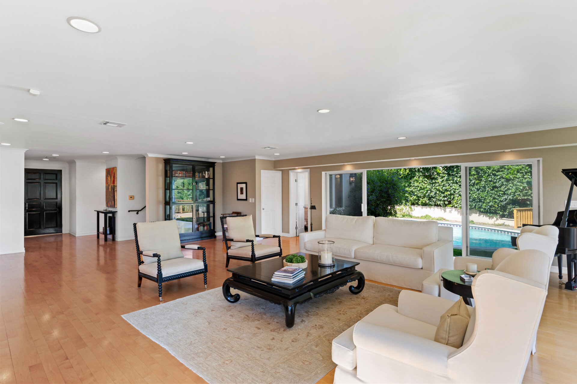 Wide-plank hardwood floors, recessed lighting, and a neutral palette create a bright setting, while multiple sliding glass doors open to the backyard.