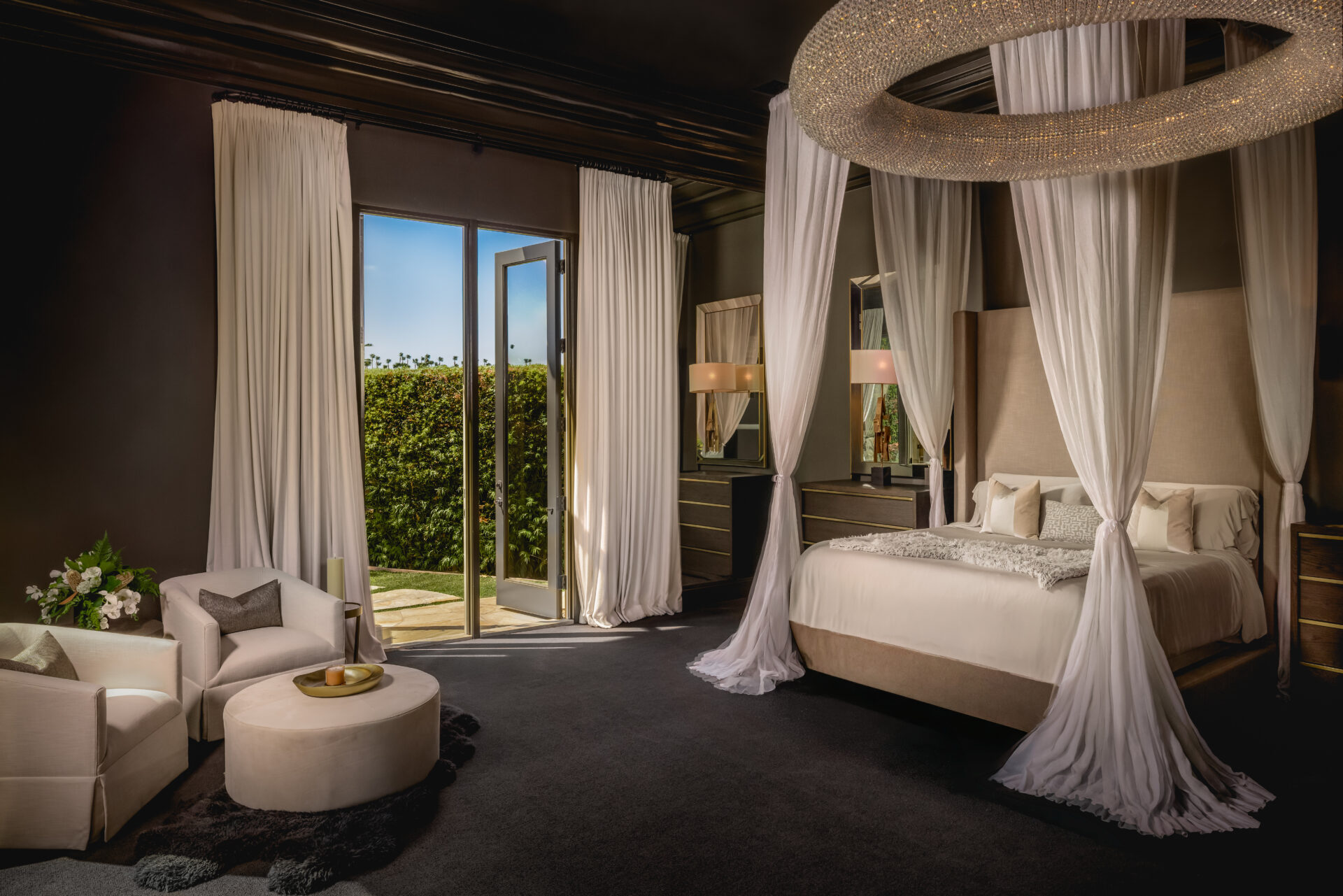 The bedroom is wrapped in deep charcoal walls and matching ceiling trim, with a four-poster bed draped in white fabric.