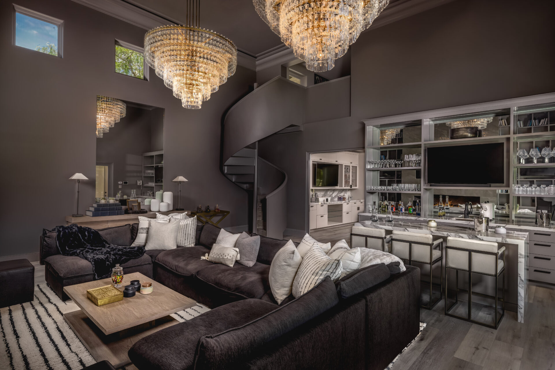 The bar lounge opens into a double-height space with two oversized crystal chandeliers suspended above a large sectional seating area. 