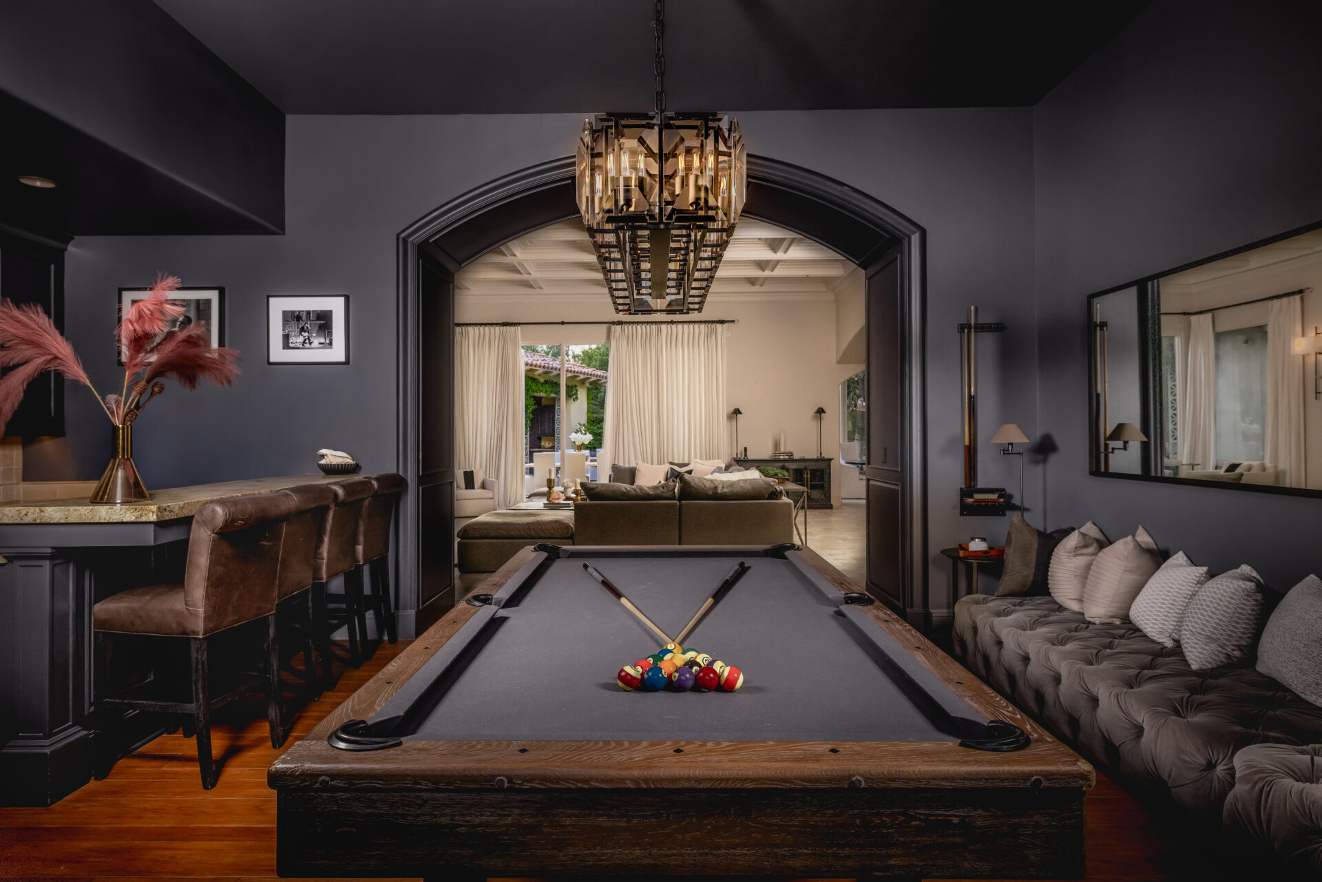 A tufted banquette extends along one wall, while a small bar with leather stools lines the opposite side.