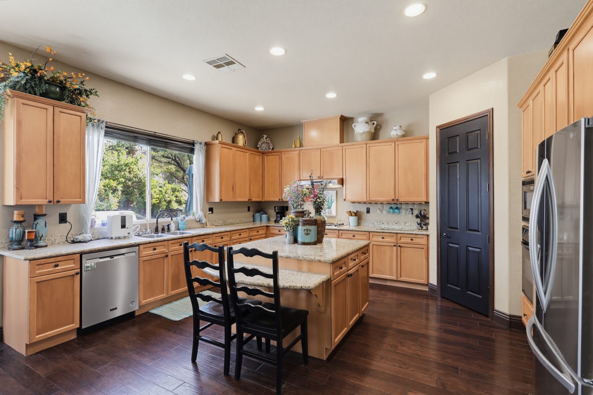 Kitchen with warm wood cabinetry paired with granite countertops and dark hardware. 