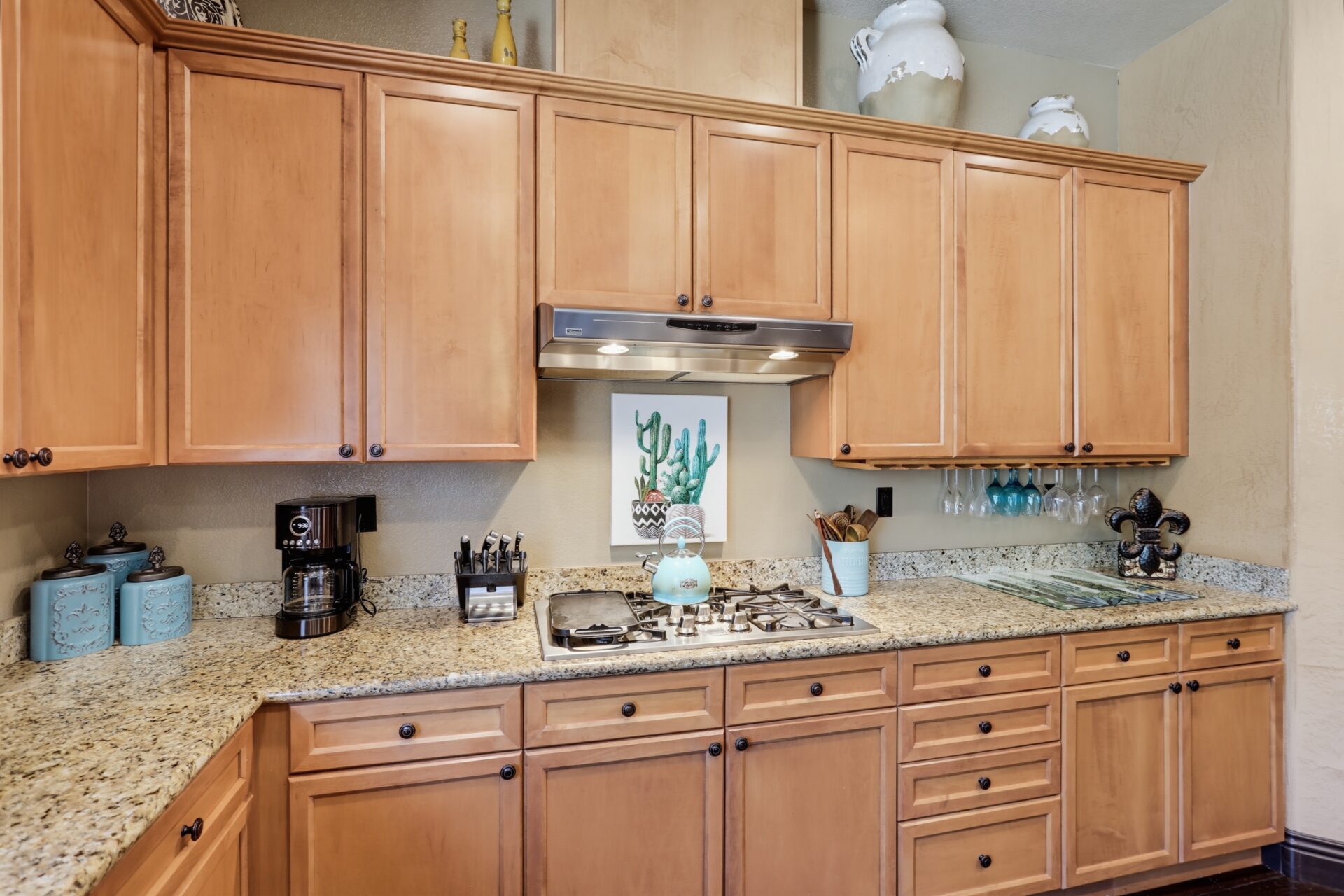 A gas cooktop integrated within marble counters with warm wood cabinets overhead and underneath the stove.