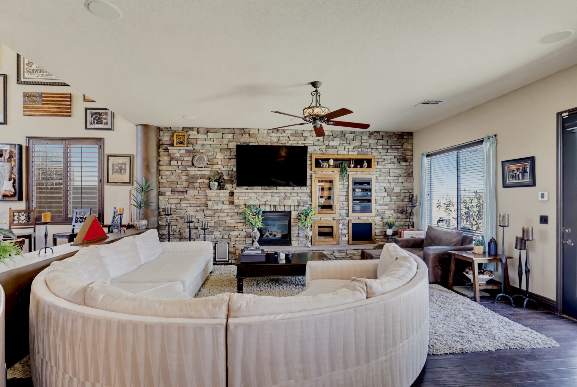 Across from a stone TV wall, a large curved sectional creates an inviting living room.