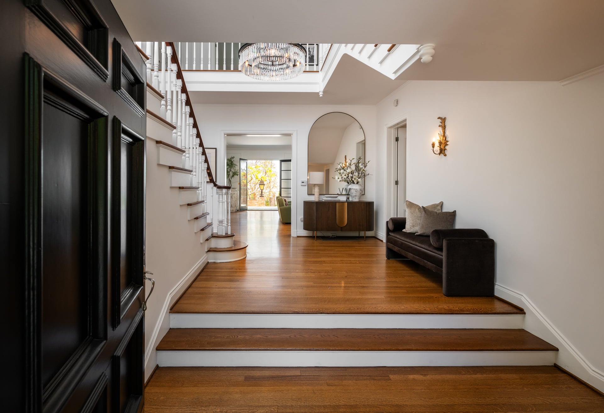 A bright foyer where a gracefully curving staircase rises to the second level beneath a crystal chandelier.