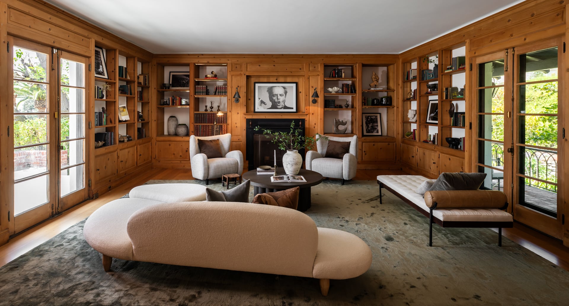 French doors on both sides bring in natural light and open to the surrounding outdoor spaces, while a mix of contemporary furniture softens the room's traditional architecture.