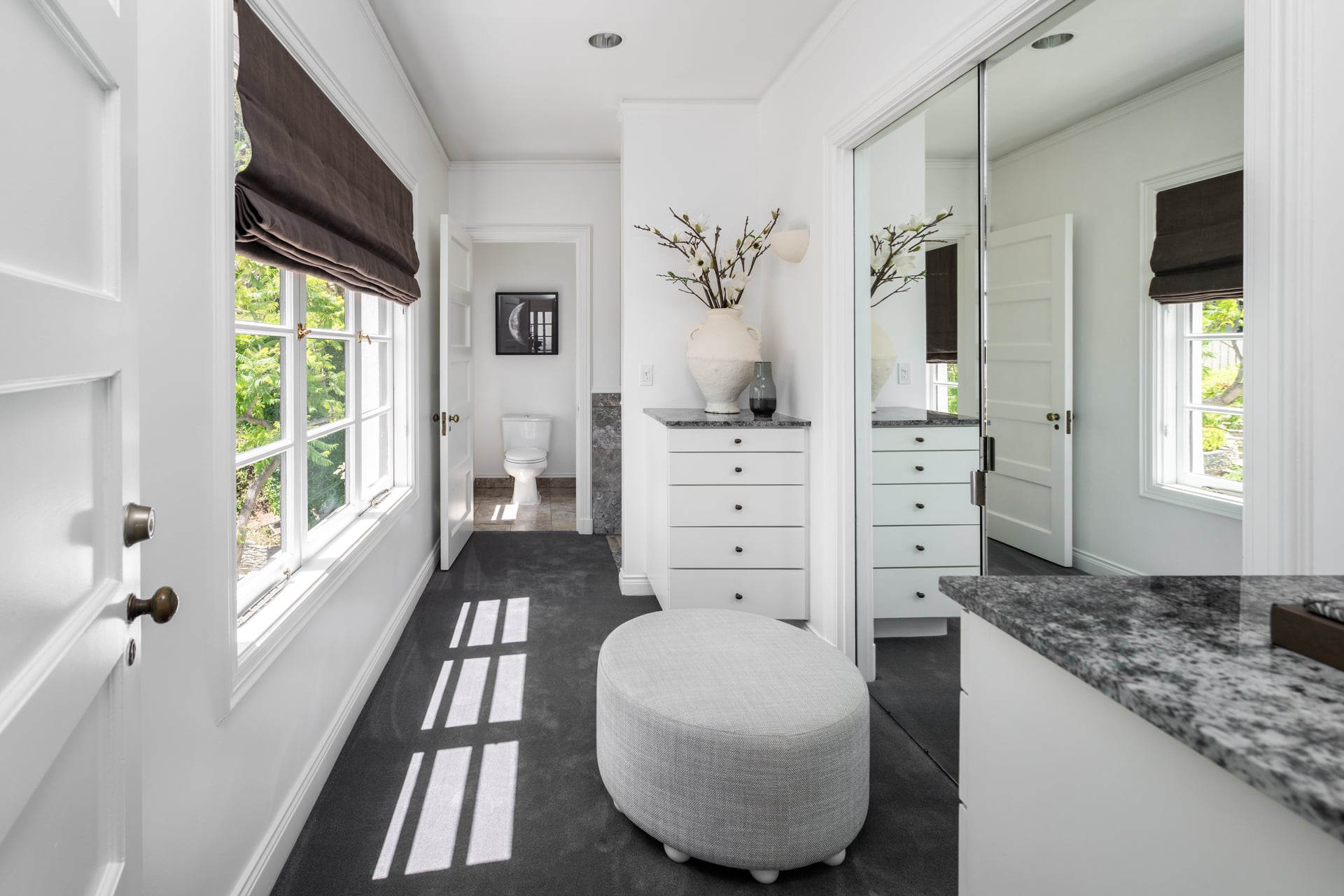 Connecting to the bedroom is a dedicated dressing room with built-in cabinetry, mirrored wardrobe doors, and granite-topped storage. 