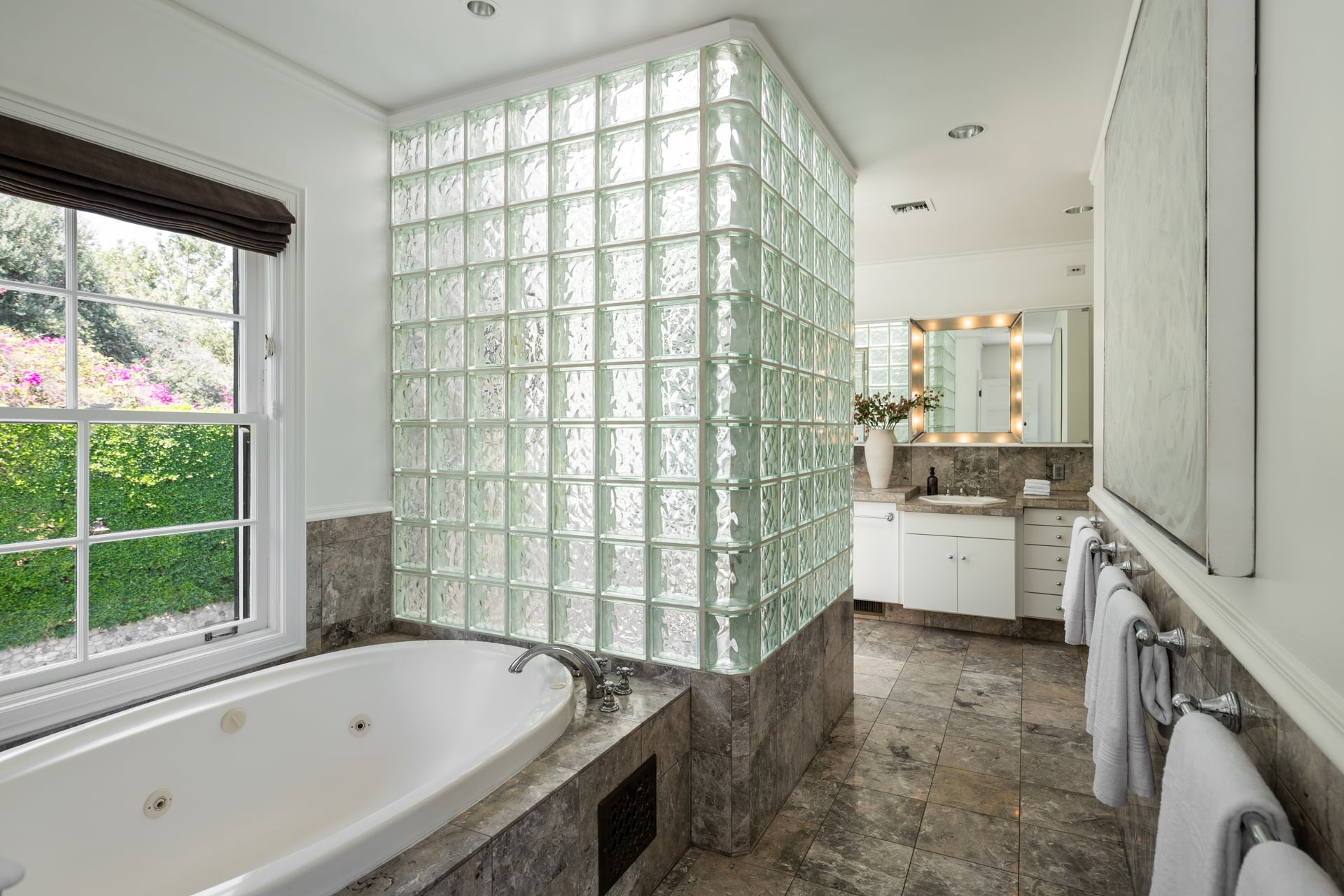 Heading into the bathroom, marble floors are paired with a soaking tub, glass-squared walked in shower, and a double vanity.
