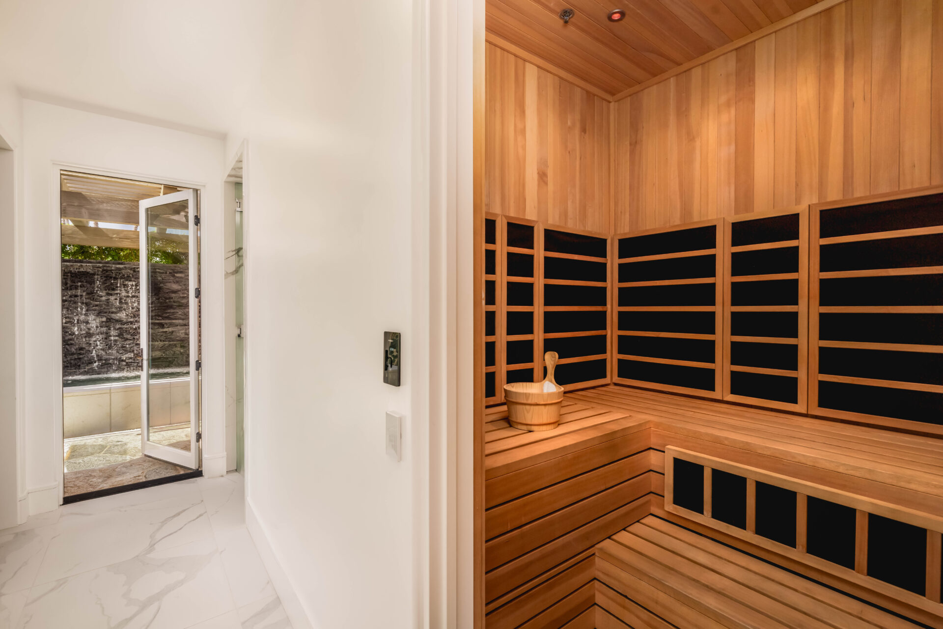 The recovery center includes a wood-lined sauna with tiered benches, along with steam facilities and hot and cold plunges positioned nearby.