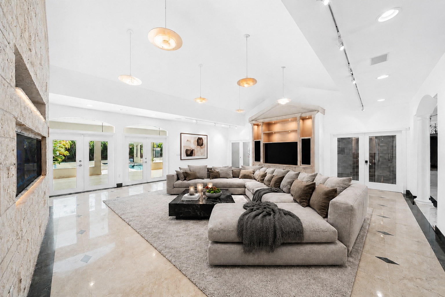A spacious family room centered around an oversized sectional that wraps around a low black stone coffee table. 