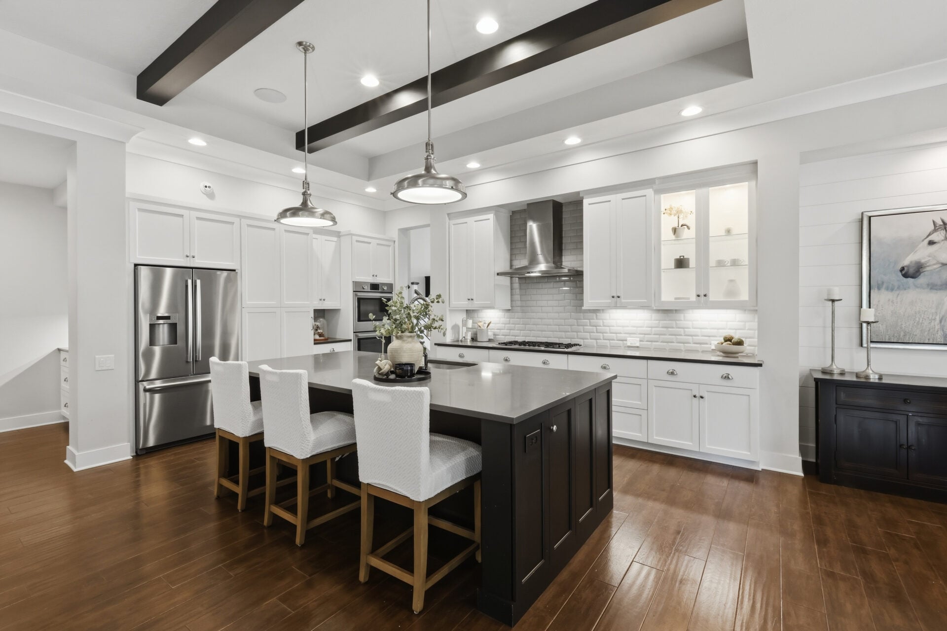 The kitchen takes up the center of the great room with an oversized island finished in dark cabinetry and lined with seating for casual meals. 