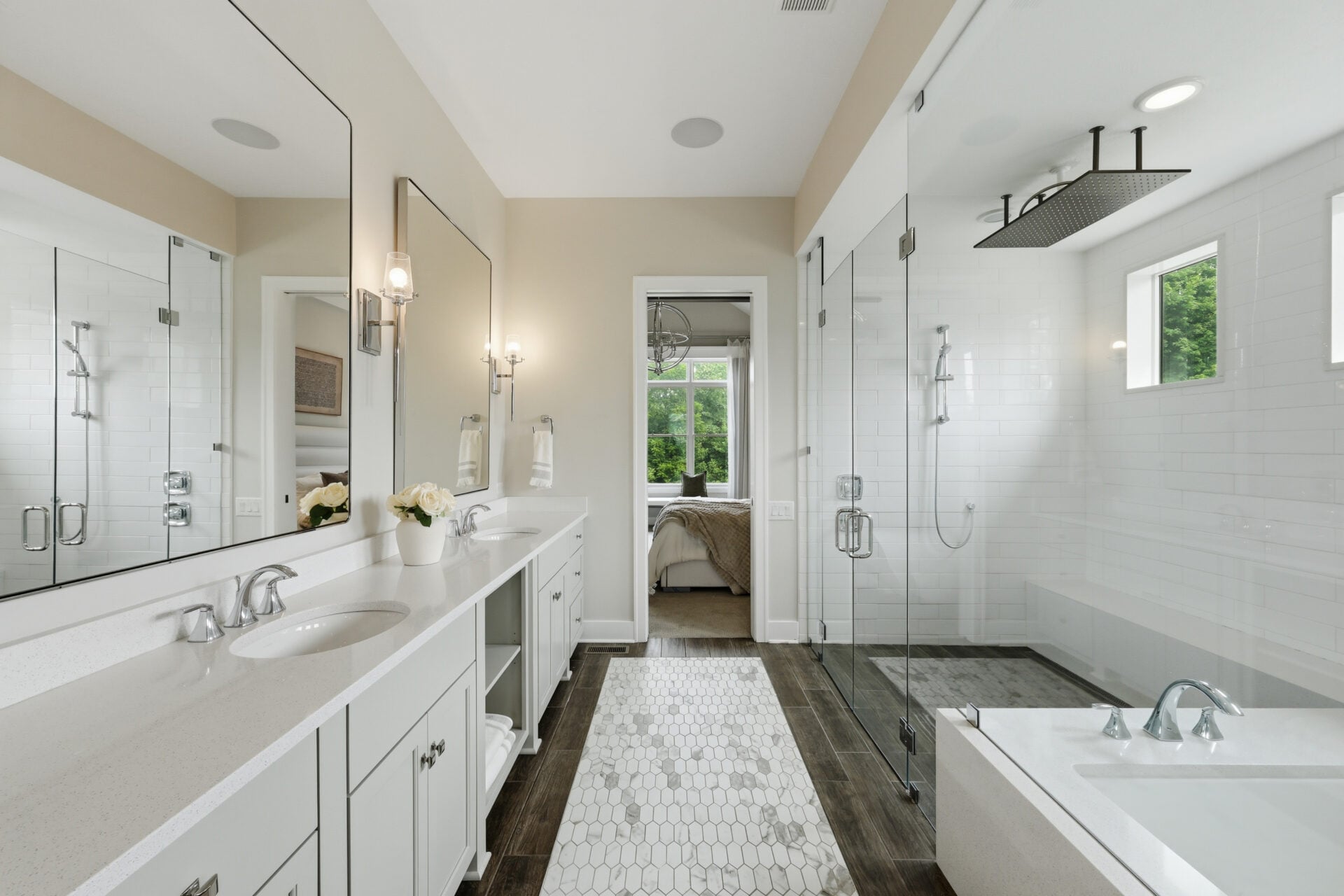 The primary bathroom has a long dual-sink vanity that stretches along an entire side of the room across from a large walk-in shower and soaking tub.