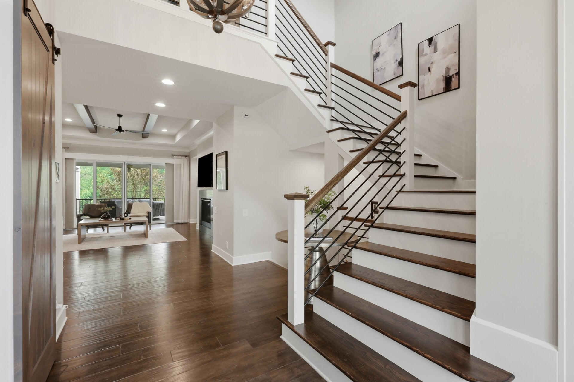 A two-story foyer where dark hardwood floors run throughout the main level, and natural light fills the space from the rooms beyond. 