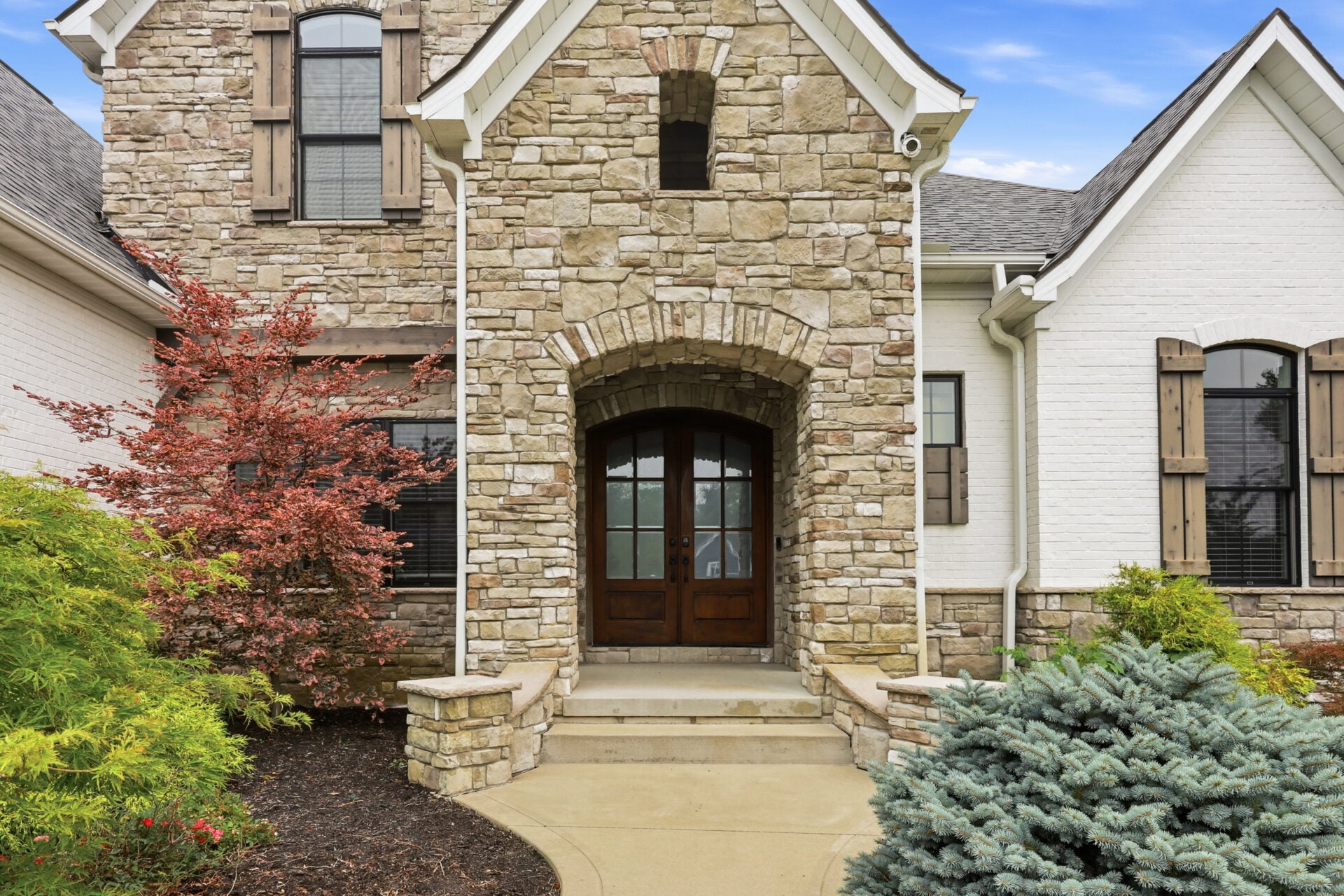 A soaring stone tower frames a recessed arched entry with double wood-and-glass doors.