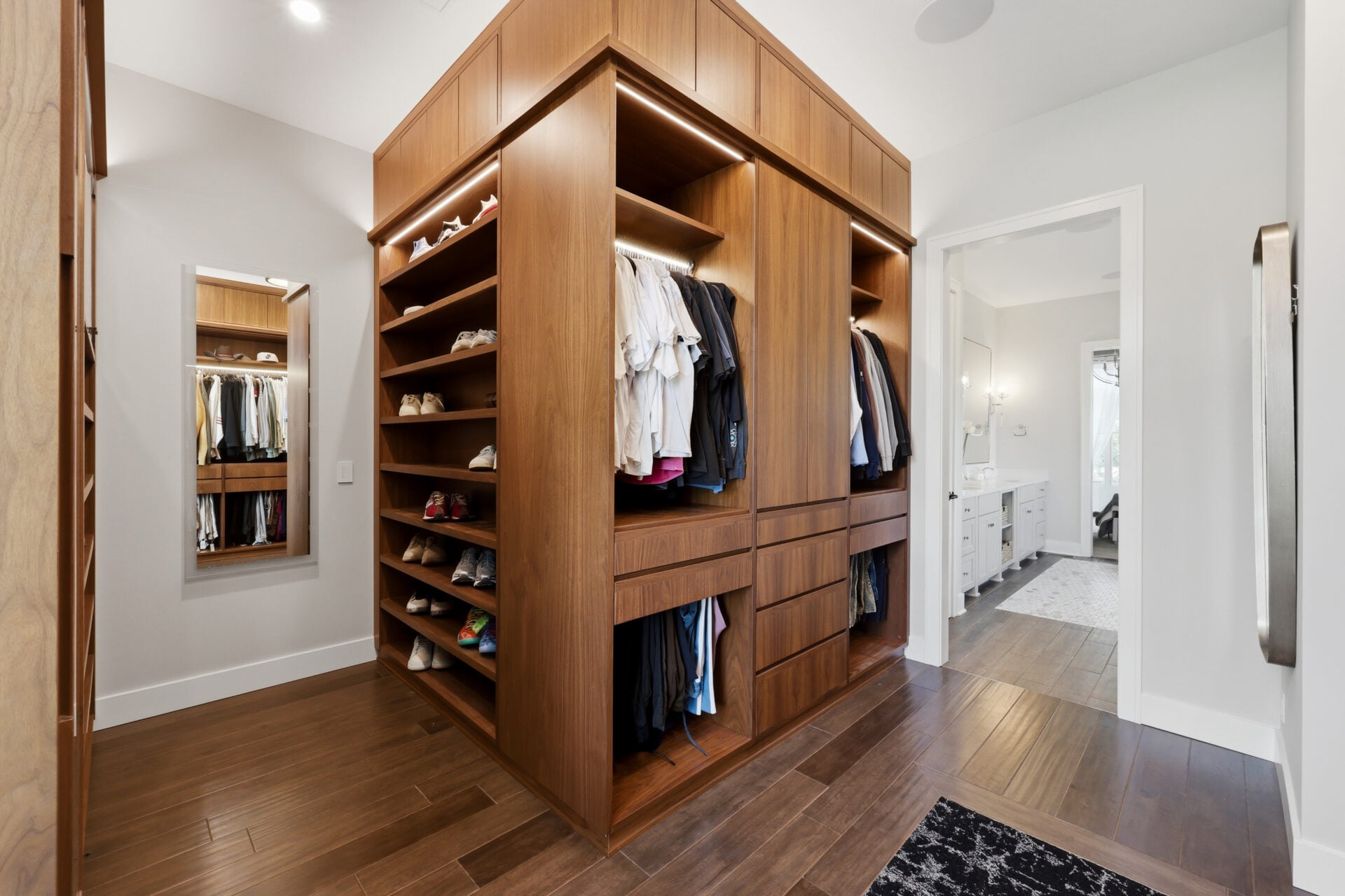 Completing the suite is the custom walk-in closet, which consists of multiple built-in wood cabinets with hanging storage, shelving, drawers, and dedicated shoe displays.