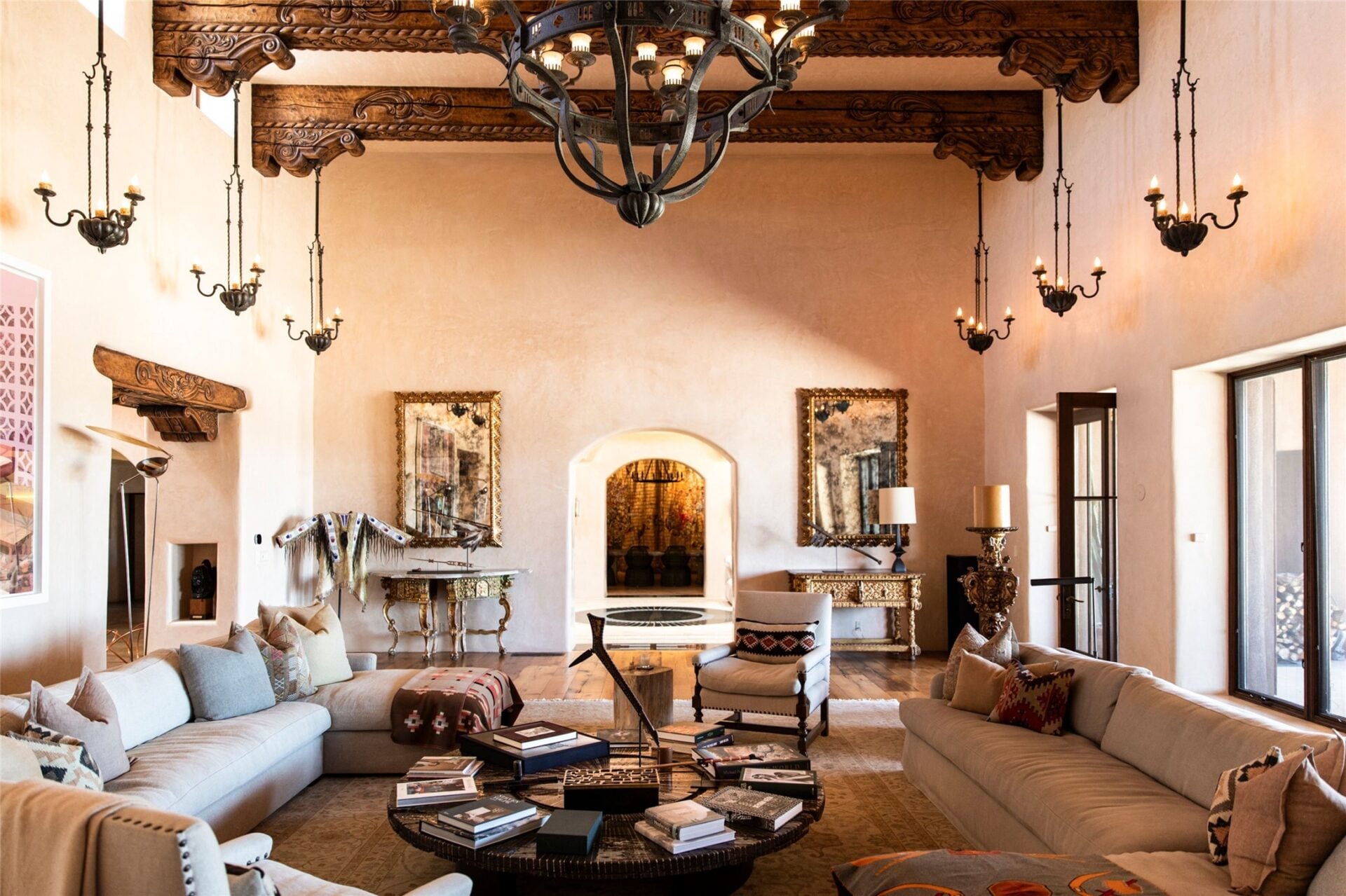 A large iron chandelier hangs over the center of the space, joined by smaller suspended fixtures that descend along both walls and emphasize the room’s height.