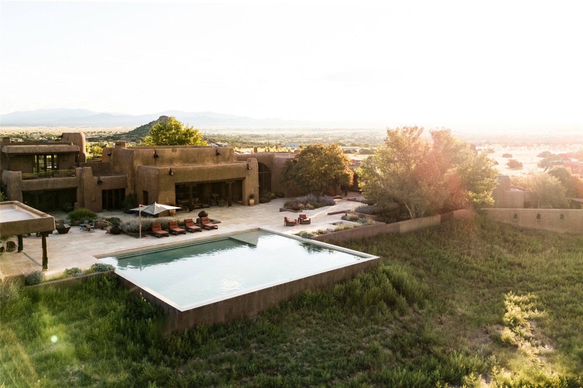 An infinity-edge pool projects toward the open desert, with its far edge aligned to the distant ridgeline and views across the valley. 