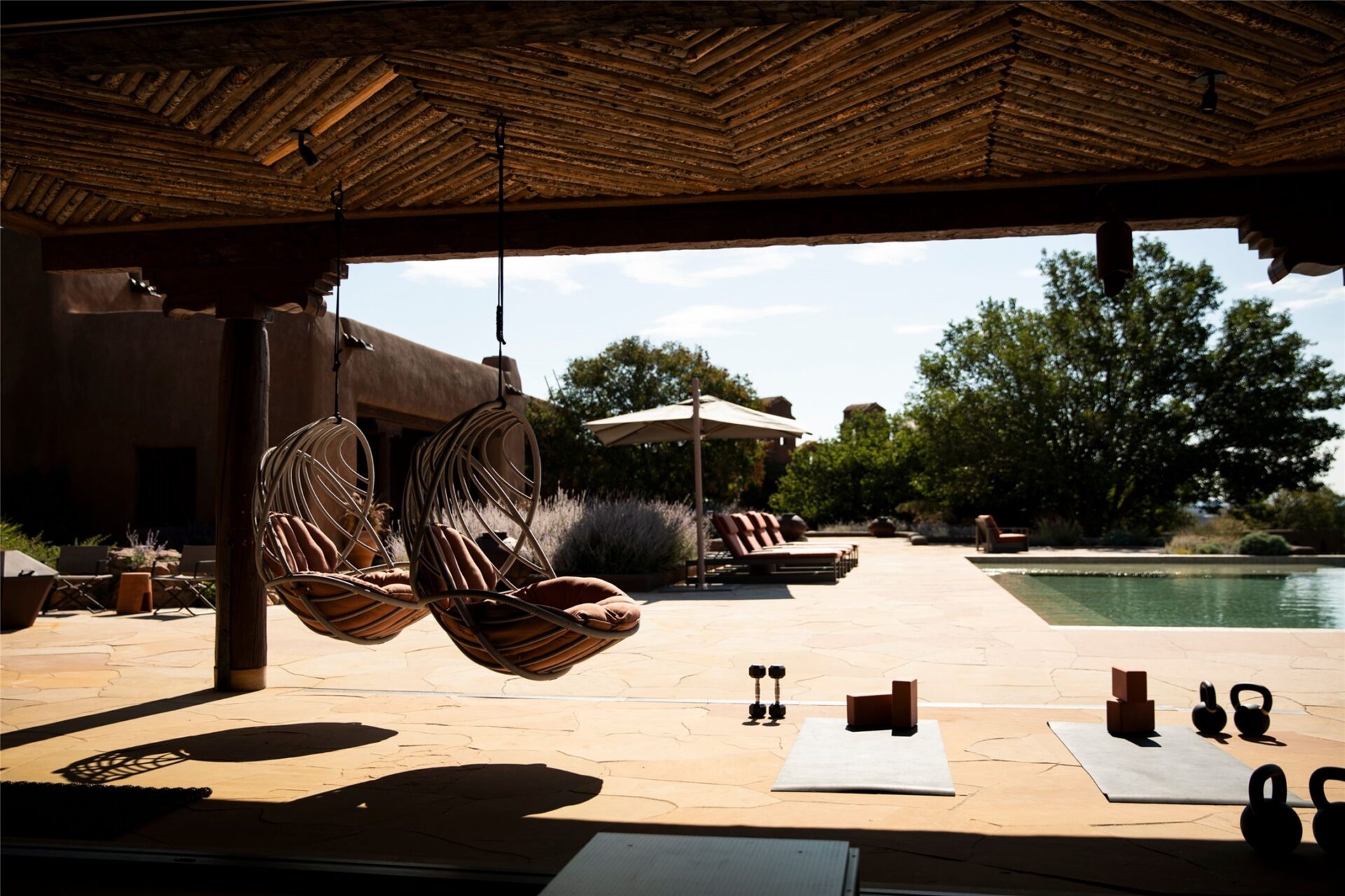 Hanging chairs and additional workout stations sit just outside, with the pool deck and surrounding grounds remaining in full view.