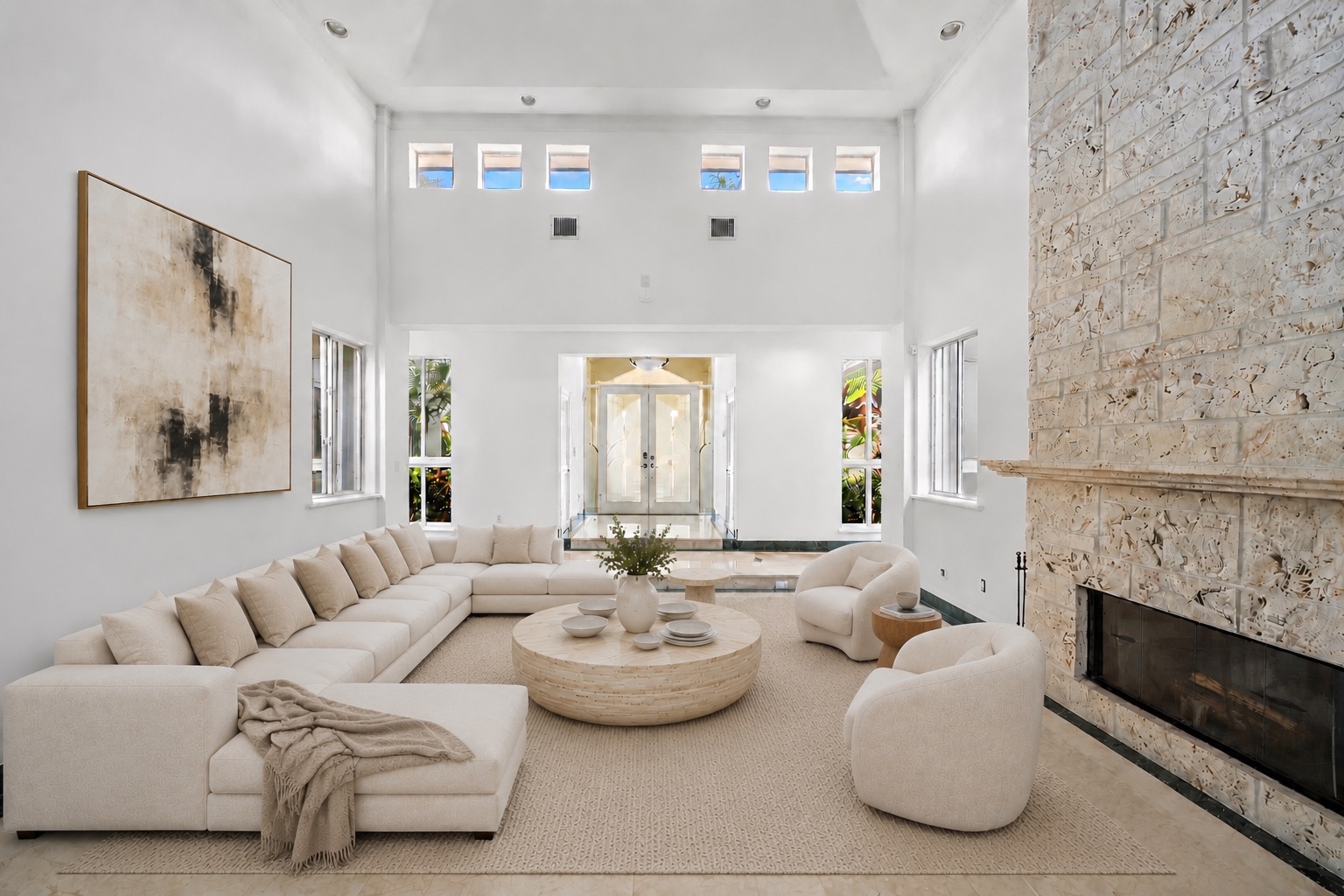 The home opens into a double-height formal living room centered around a large seating arrangement beneath the soaring ceiling. 