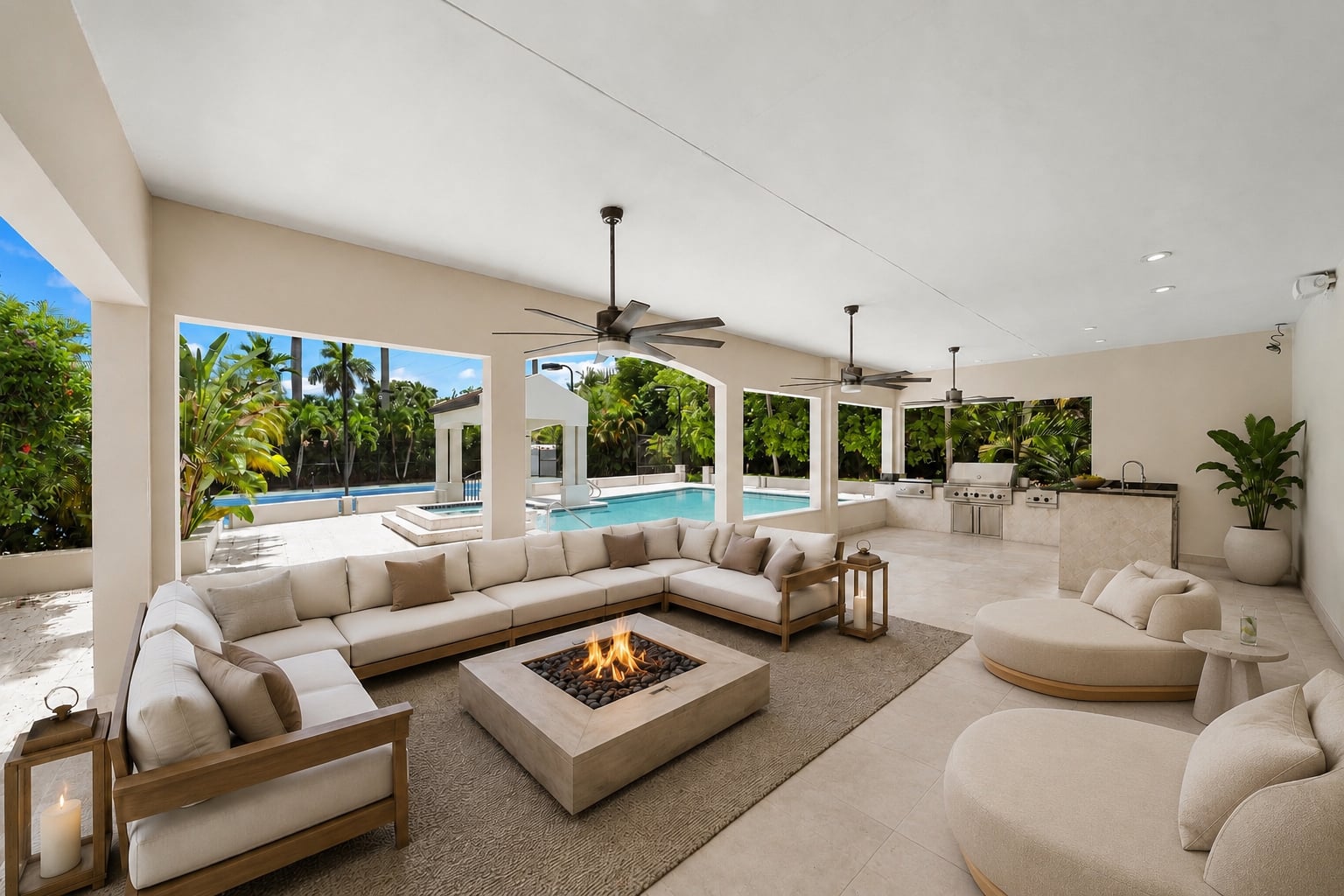 The covered patio functions as an outdoor living room with multiple seating areas arranged around a square fire pit and an outdoor kitchen.