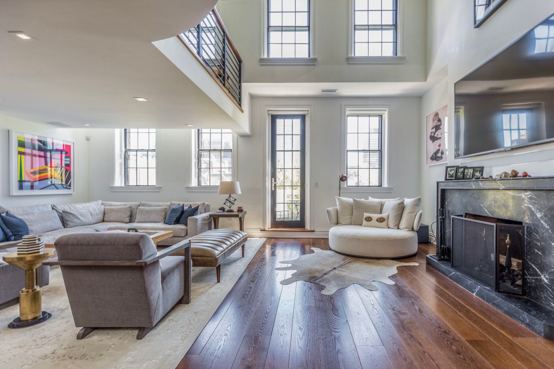 Rich stained hardwood floors run throughout, while a statuary marble fireplace sits across from the seating arrangement.