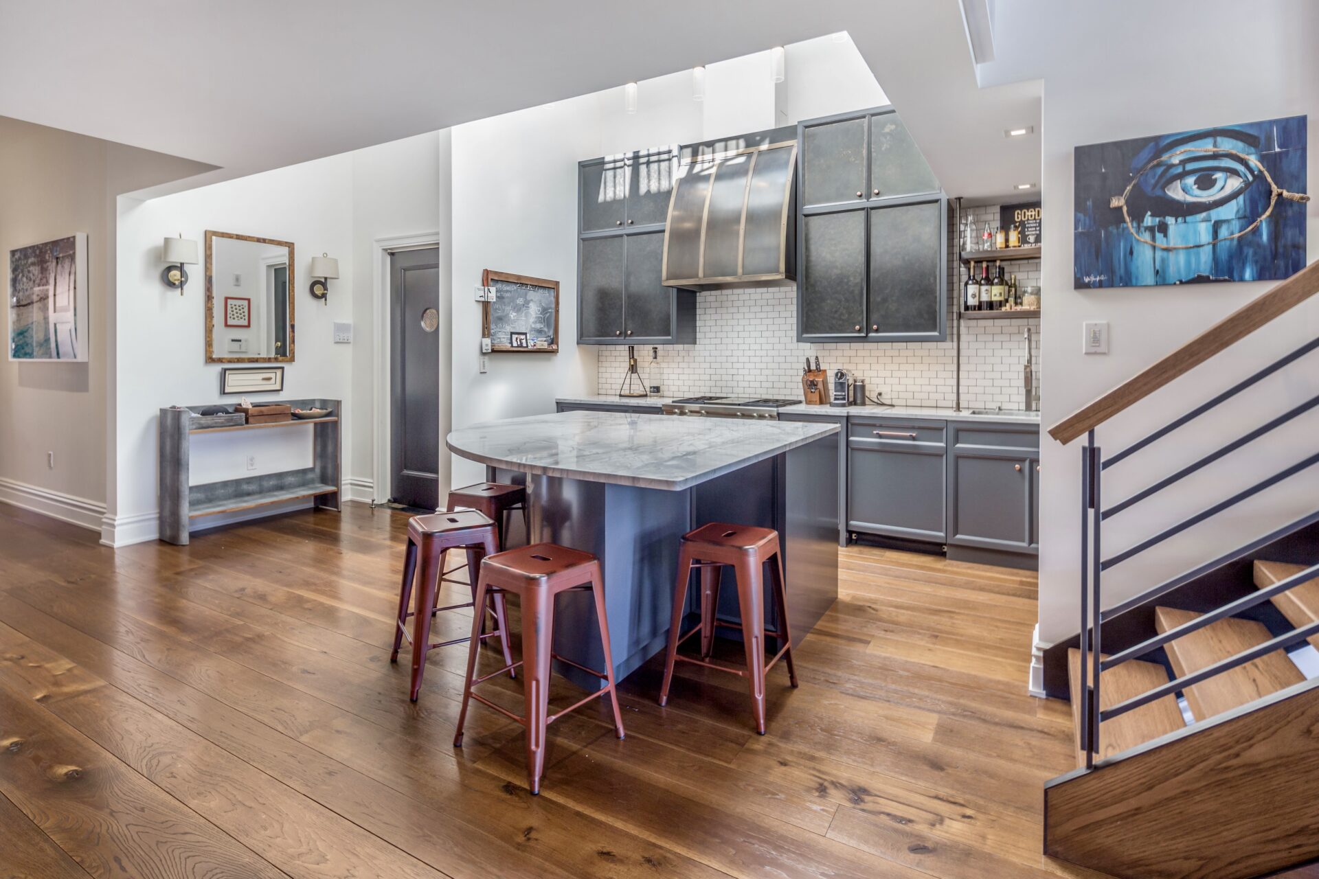 Kitchen with custom cabinetry finished in rich charcoal, stone countertops, and a curved center island.