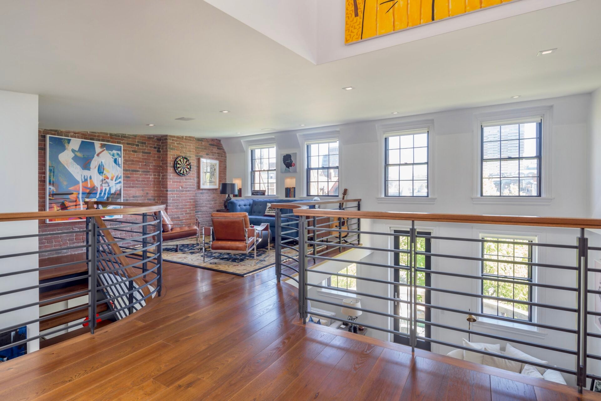 A seating area tucked against the exposed brick wall creates a comfortable spot for reading, playing music, or a game of darts.