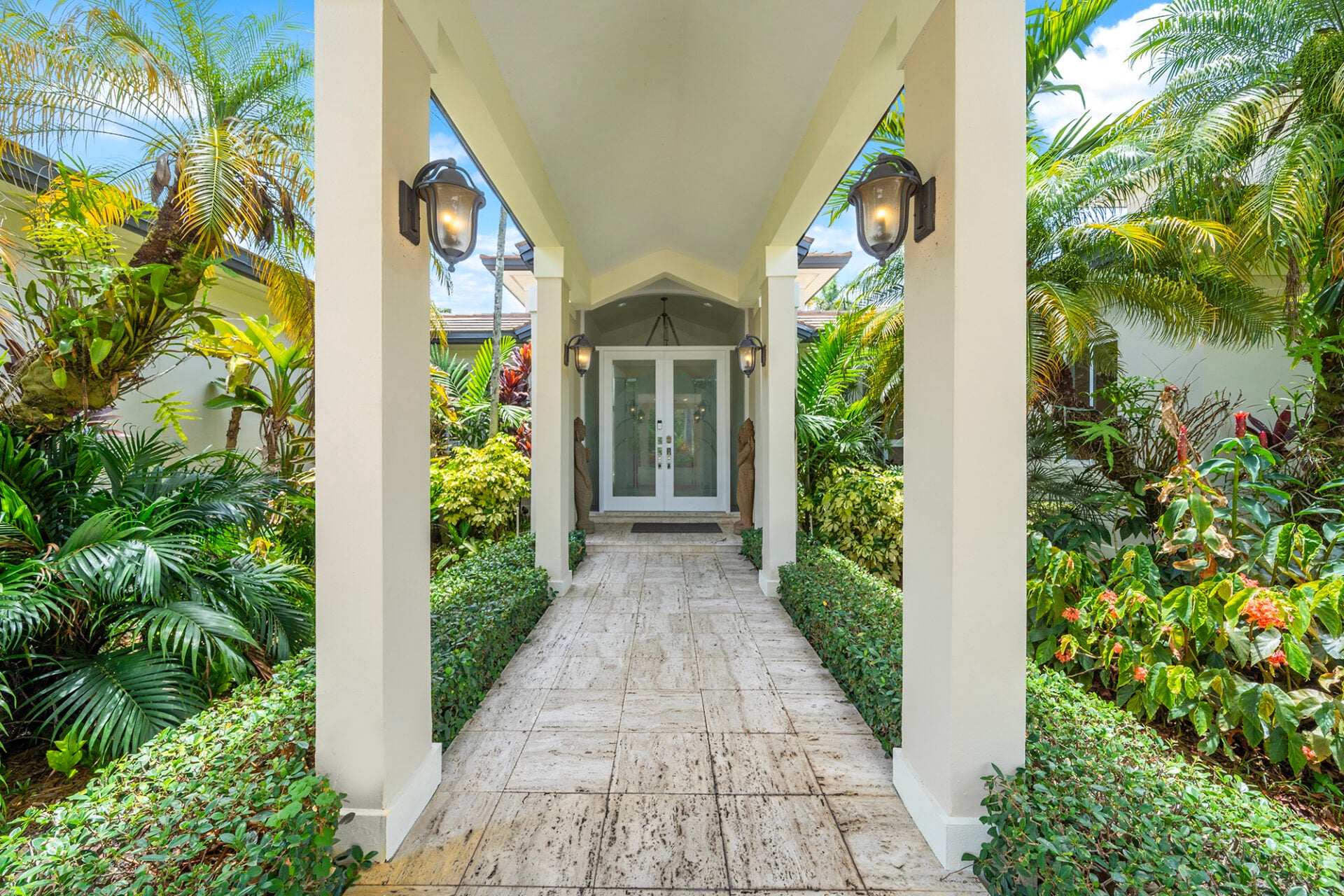 Tall columns frame the walkway leading to a set of frosted glass double doors that welcome guests into the home.