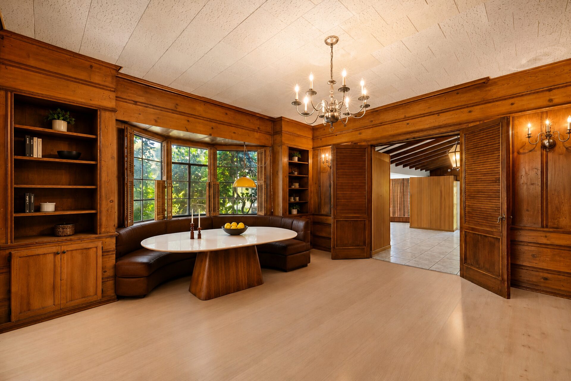 Just past the island, the kitchen flows into a cozy breakfast nook with built-in banquette seating tucked into a curved bay of windows framed by built-in shelving.