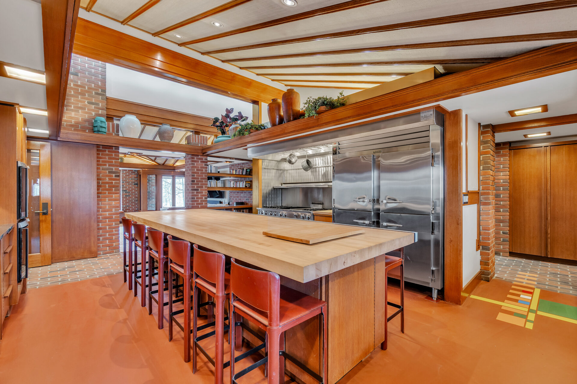 A massive butcher-block island provides seating for twelve, while professional stainless steel appliances, including oversized refrigeration and a restaurant-style range, line one wall.