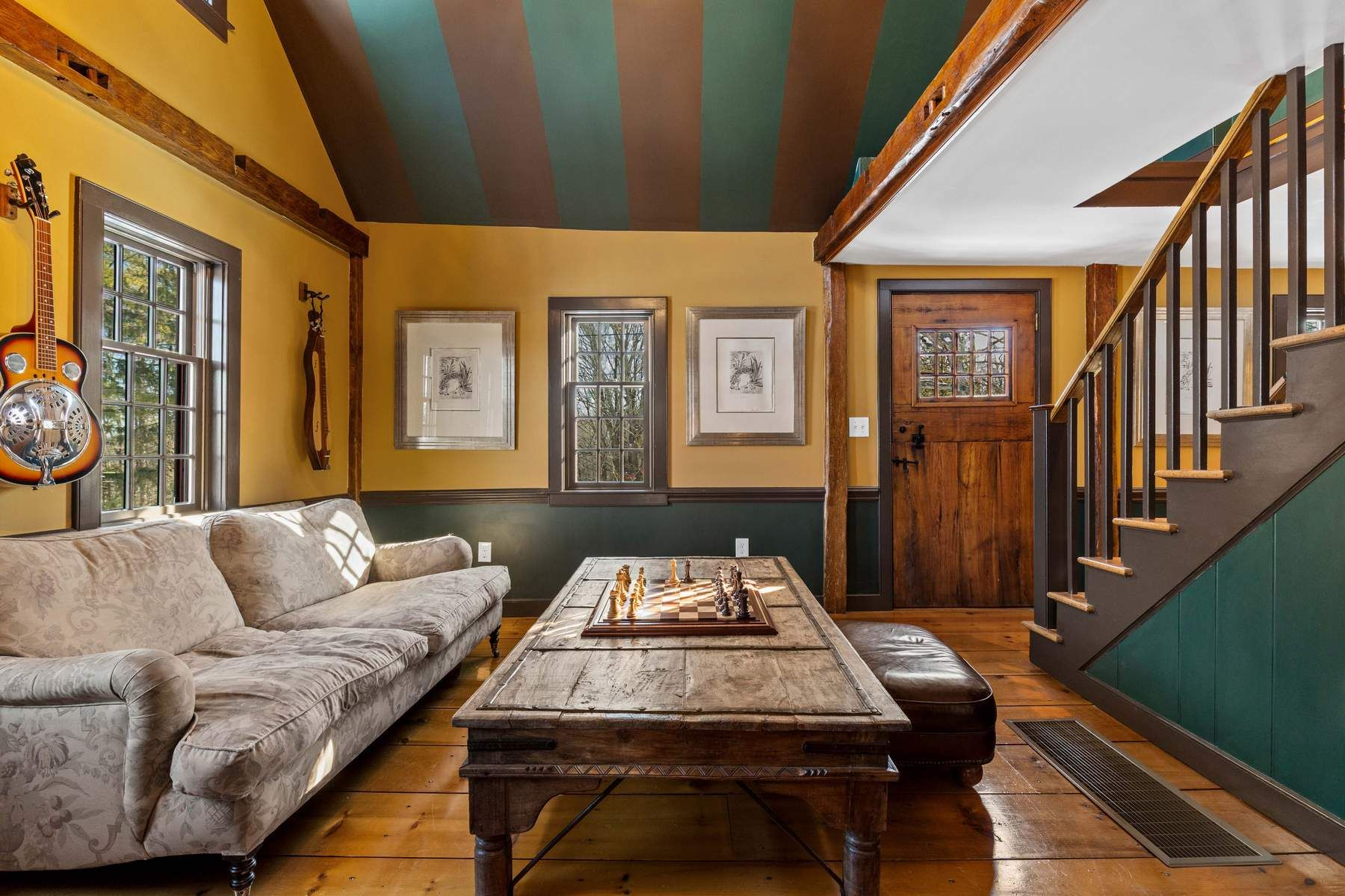 Turning toward the opposite side of the space, a staircase rises to the second floor while multiple windows fill the room with natural light.