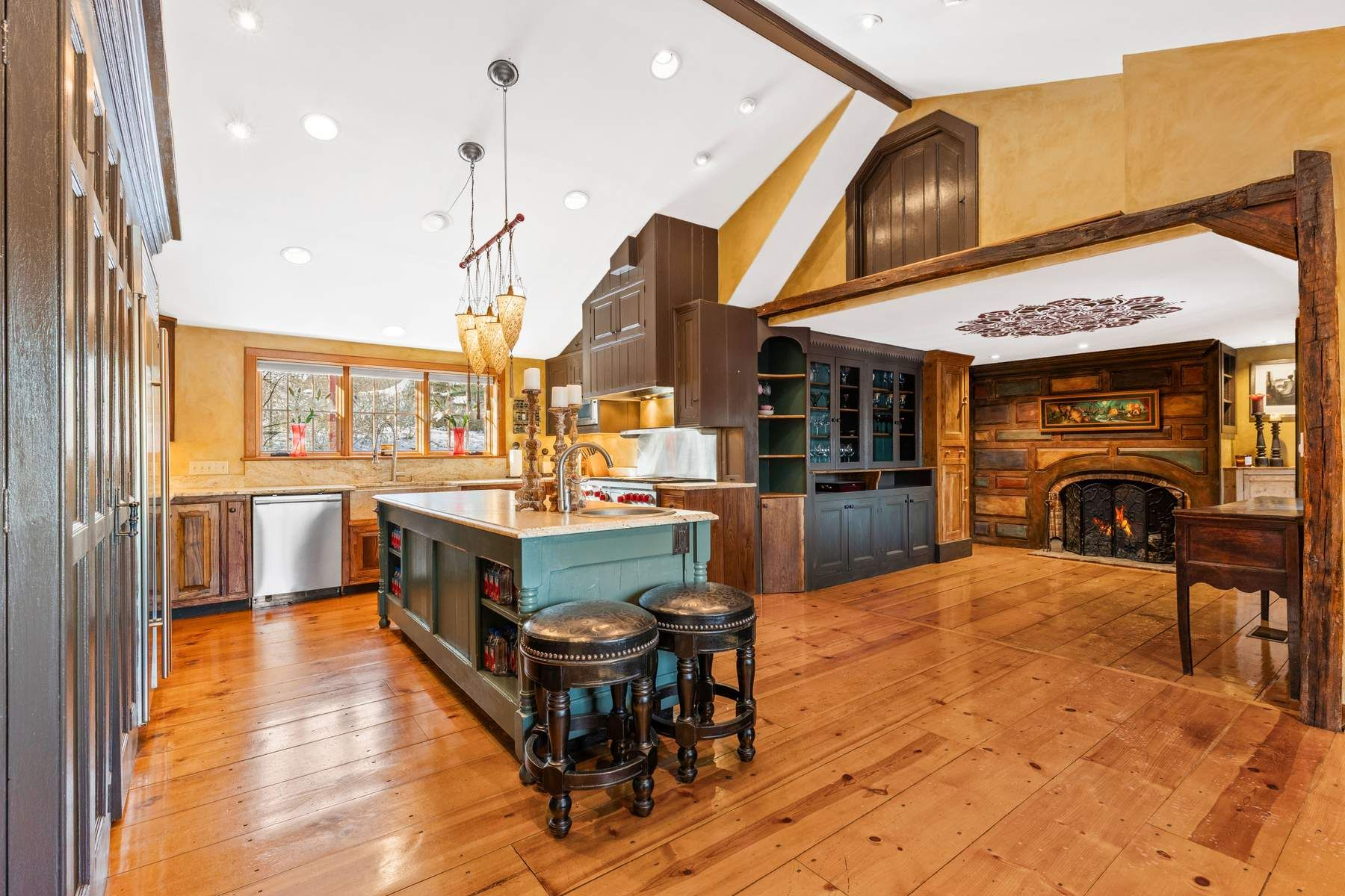 Kitchen with a large green painted island topped with granite and handcrafted wood cabinetry that extends to the vaulted ceiling.