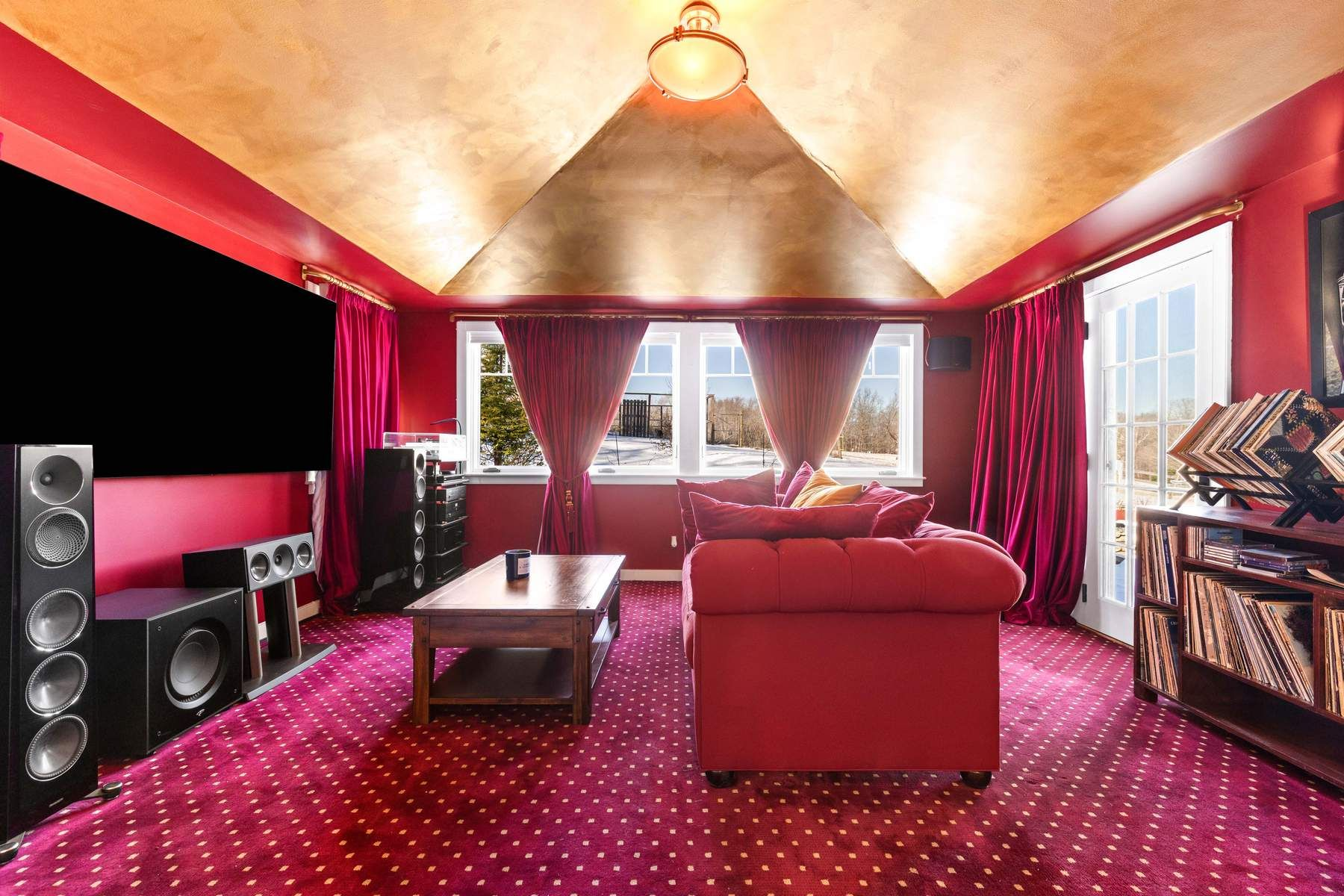 Rich red walls, matching drapery, and patterned carpeting create a dedicated theater-like setting.