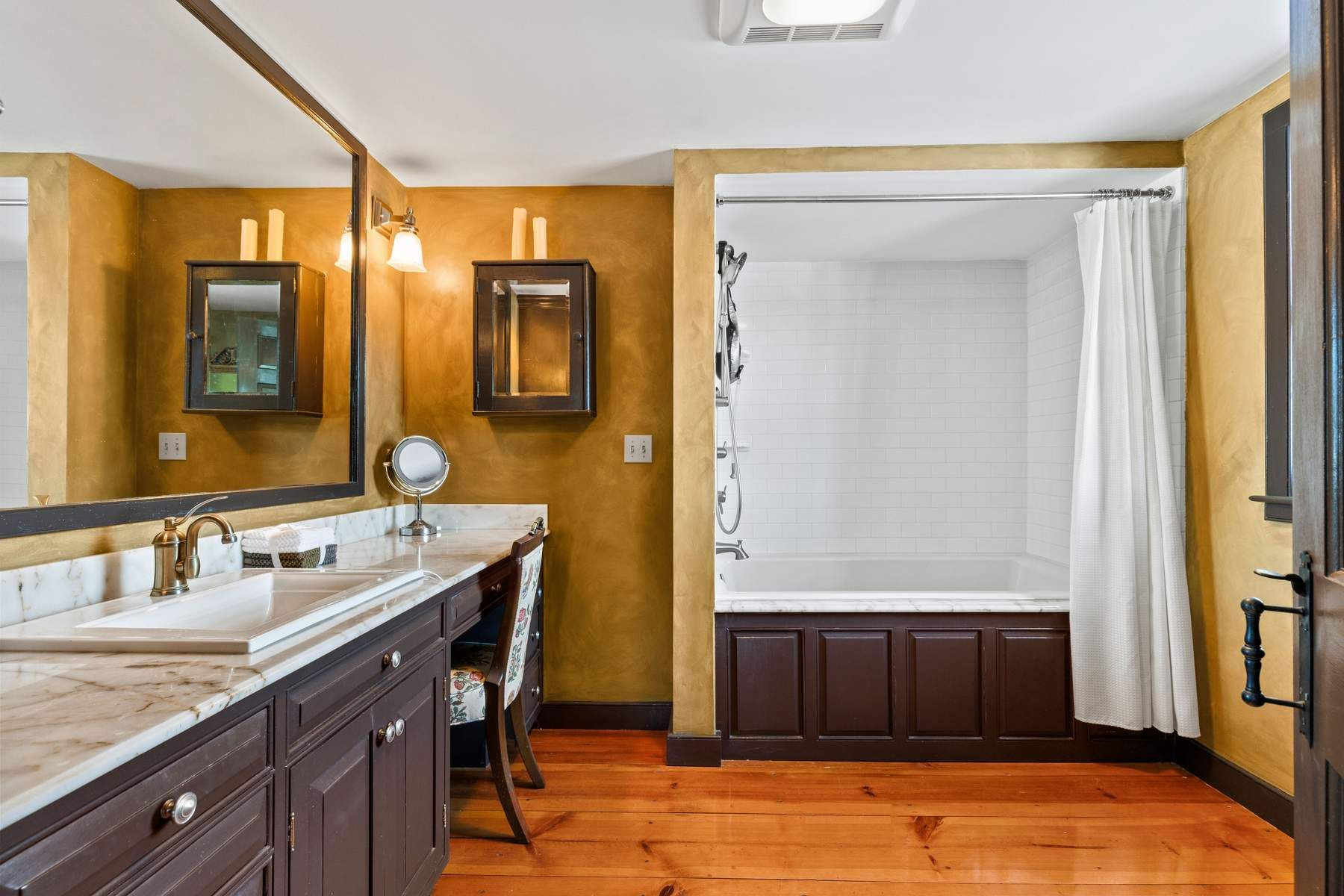 The en-suite bath features a long marble-topped vanity with built-in storage and a dedicated makeup station.