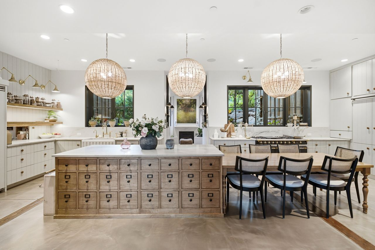 A custom La Cornue range set beneath black-framed windows overlooking the landscape. 