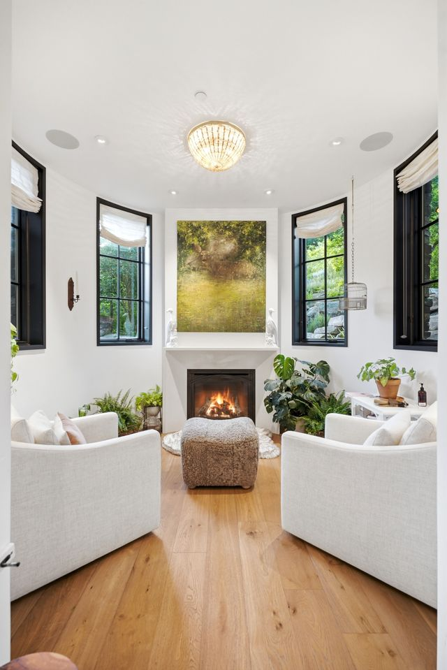 A more intimate family room centered around a fireplace beneath a large landscape painting. 