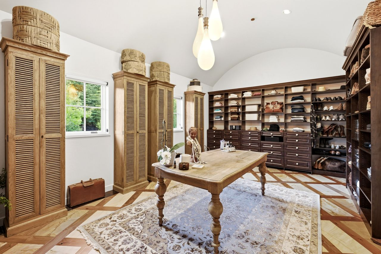 The oversized walk-in closet is lined with custom built-in shelving, rows of drawers, and floor-to-ceiling storage.