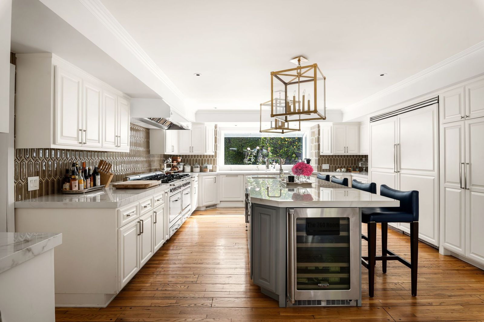 Kitchen centered around an oversized marble island that provides prep space, casual seating, and a built-in wine refrigerator. 