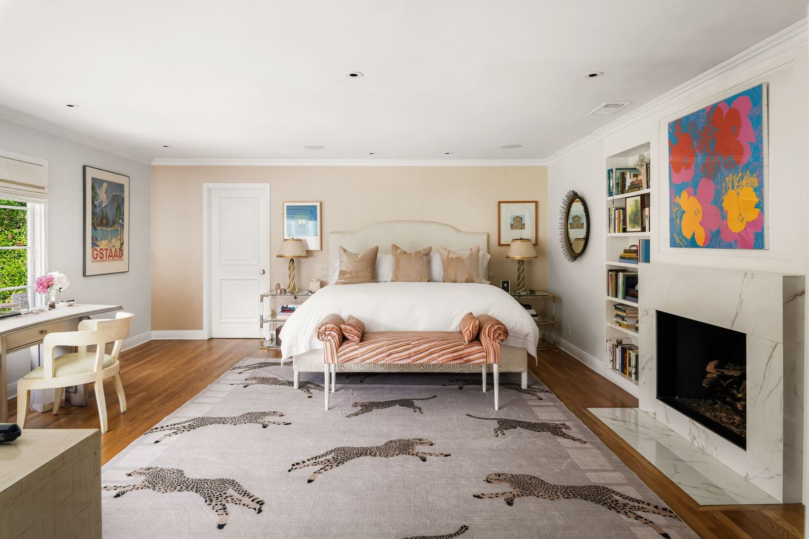 The bedroom is centered around a marble fireplace framed by built-in bookcases and topped with colorful artwork.