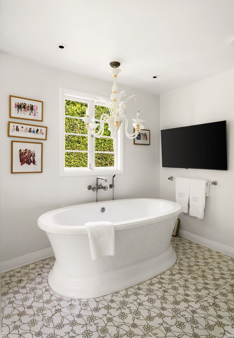 The separate soaking tub sits between a window and TV.