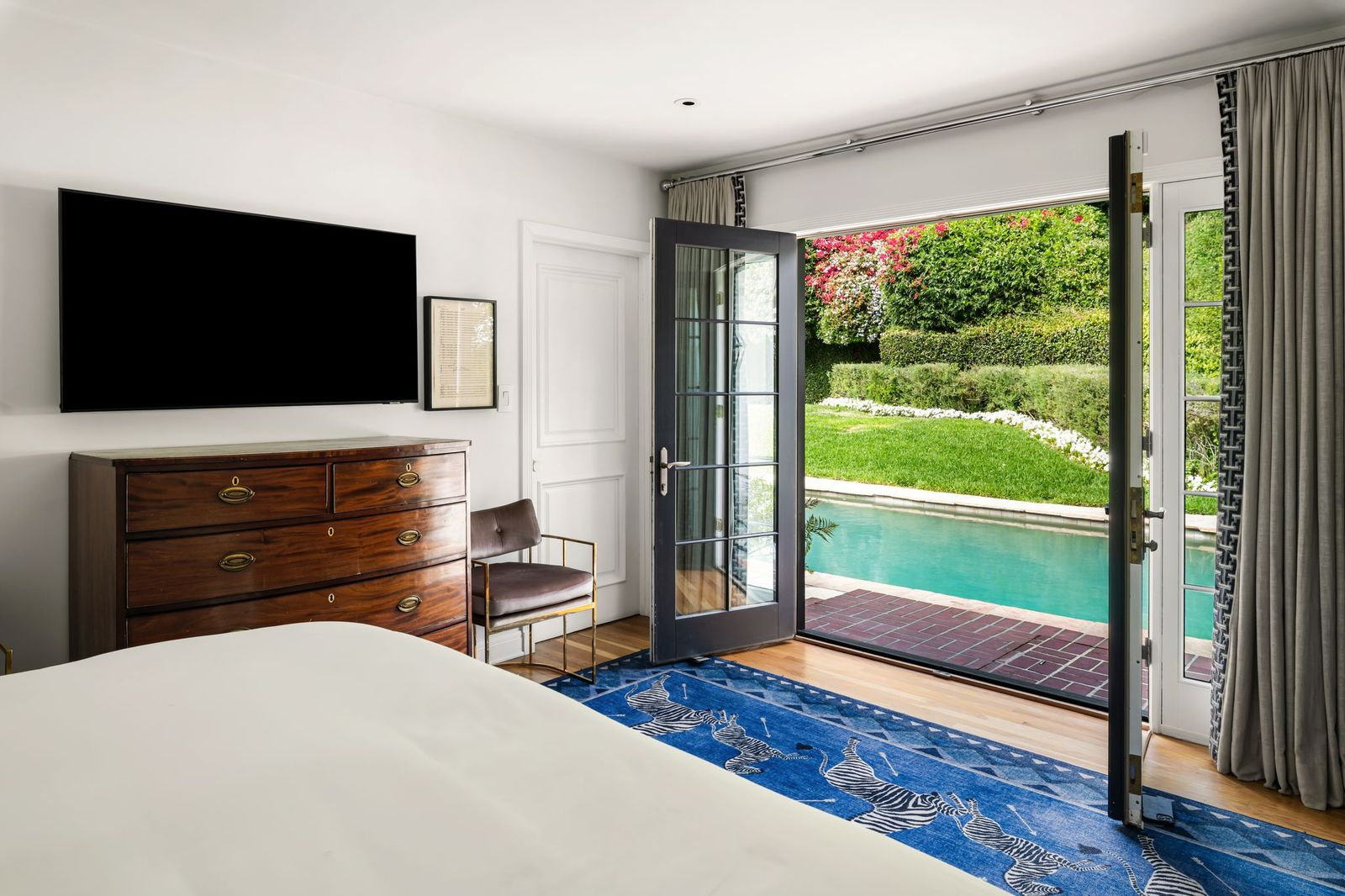 The second bedroom is positioned on the lower level with French doors that open directly to the backyard and pool terrace.