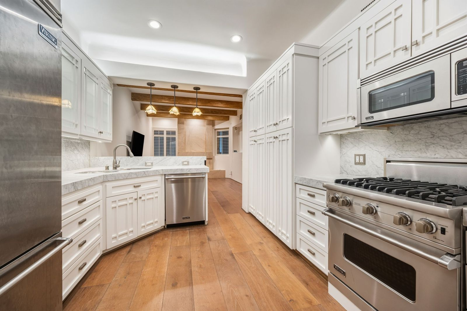 The gourmet kitchen pairs bright traditional cabinetry with warm marble countertops that extend into the backsplash. 