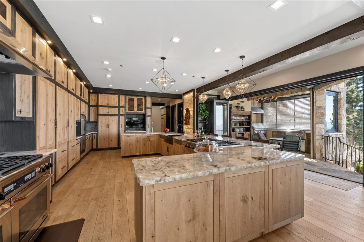 The kitchen continues the home's blend of mountain craftsmanship and modern function, centered around an oversized island topped with crystal quartz countertops featuring natural raw edges. 