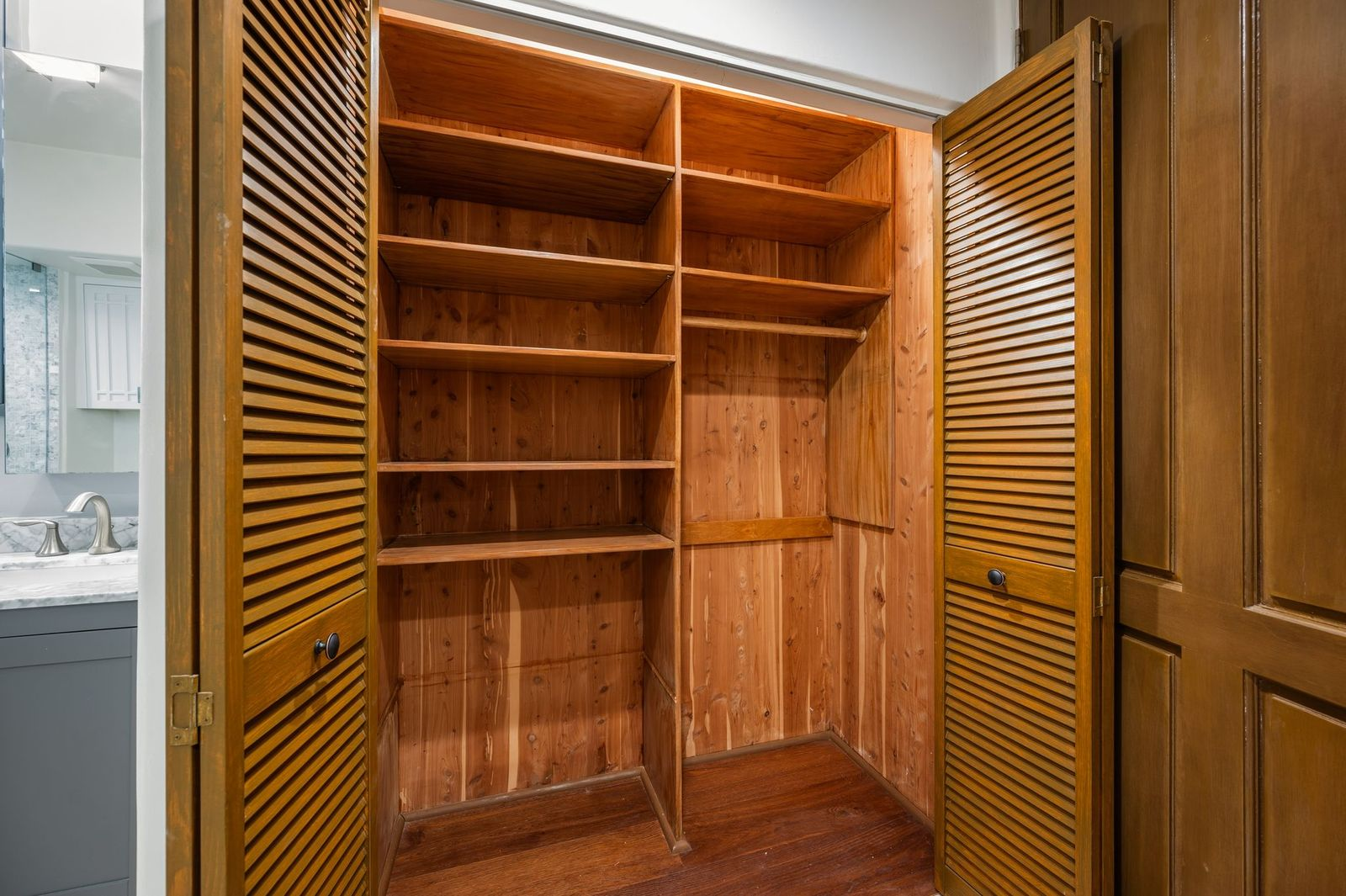 Closet with traditional wood shelving and louvered doors.
