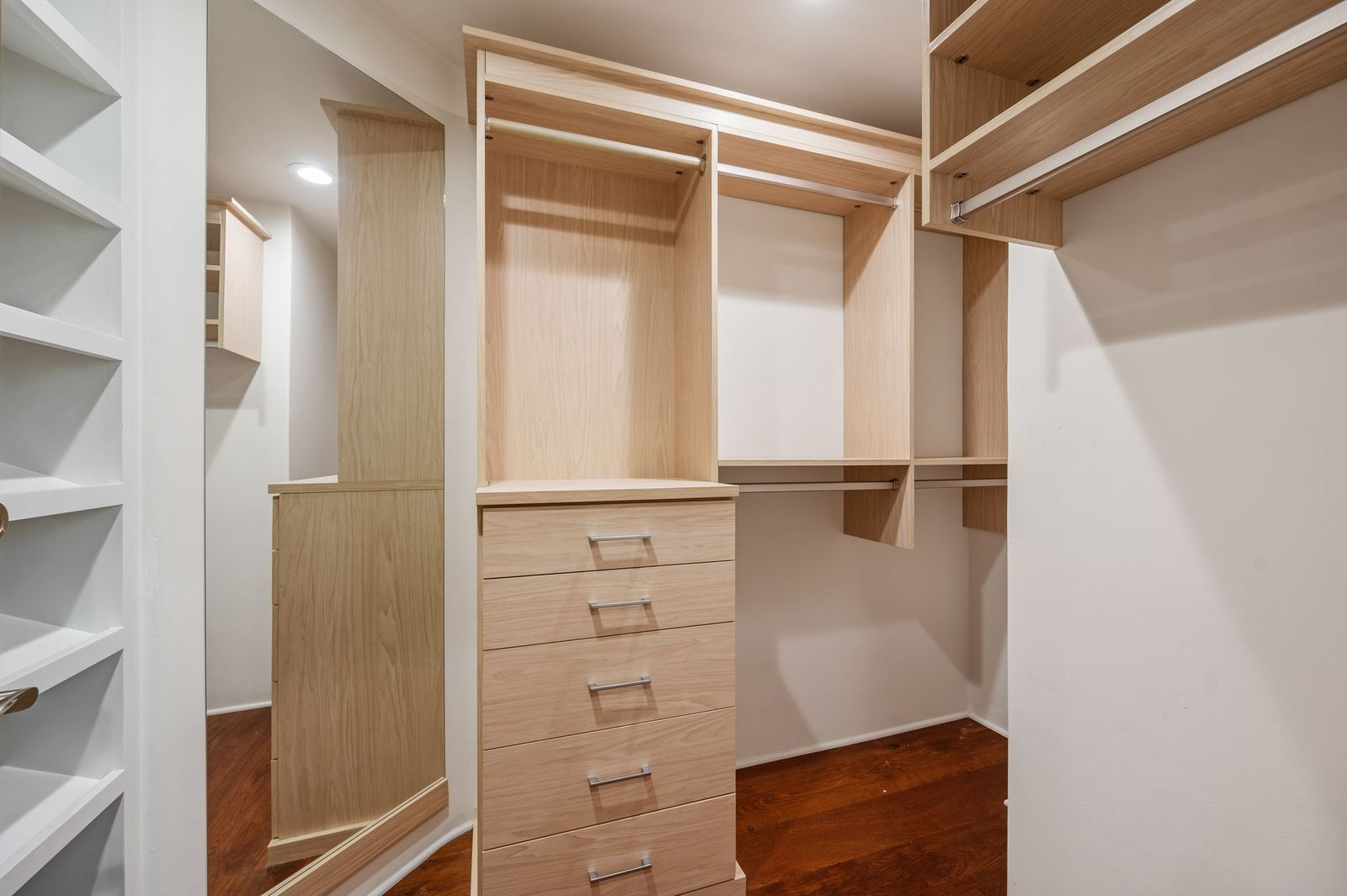 A walk-in closet with custom built-in cabinetry, drawers, hanging space, and a full-length mirror.