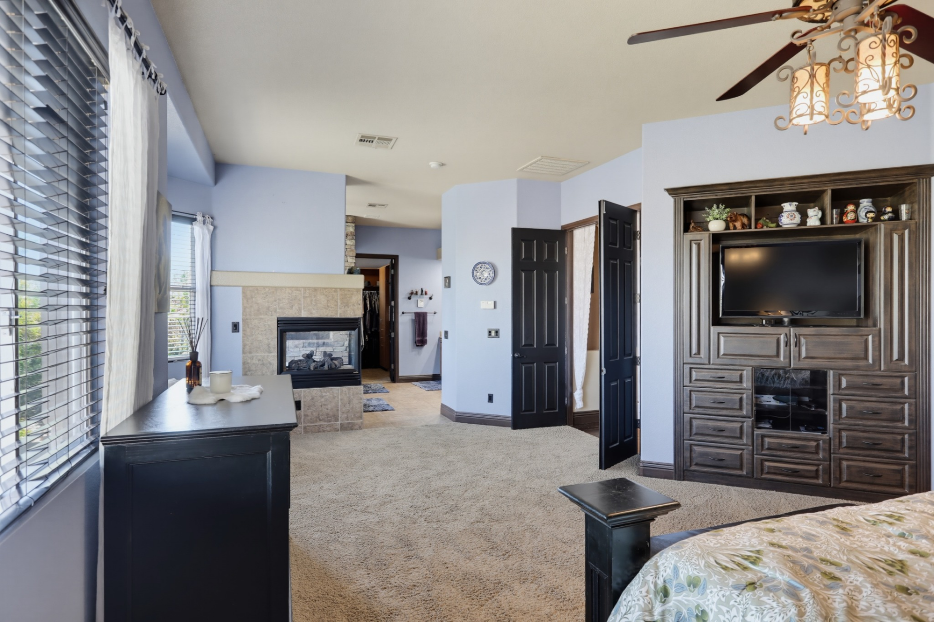 Across from the bed is a built-in media wall that combines cabinetry, drawers, and shelving around the television.
